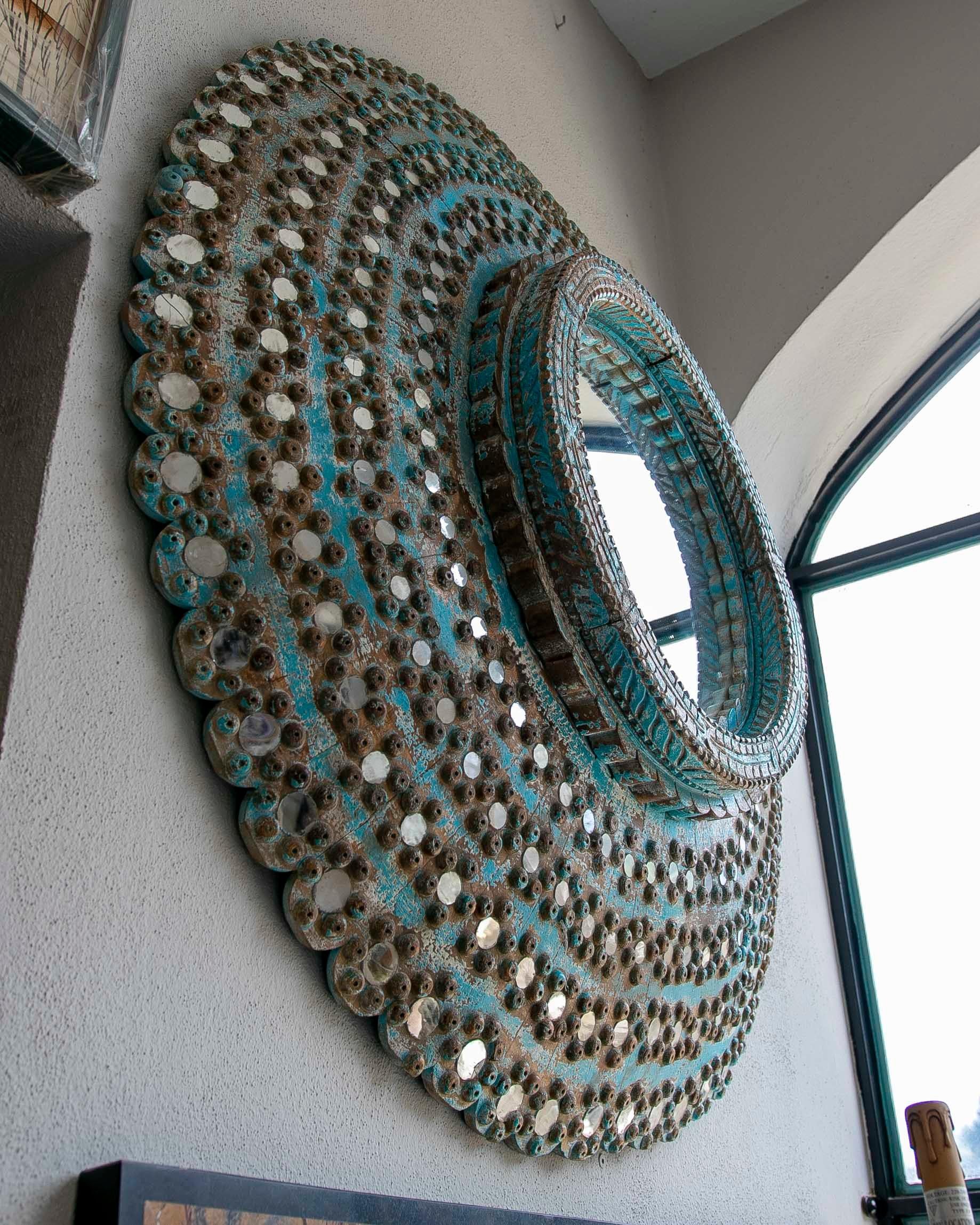 Miroir mural rond en bois polychrome dans les tons de bleu. Miroir circulaire décoré de petits miroirs et de clous en fer
