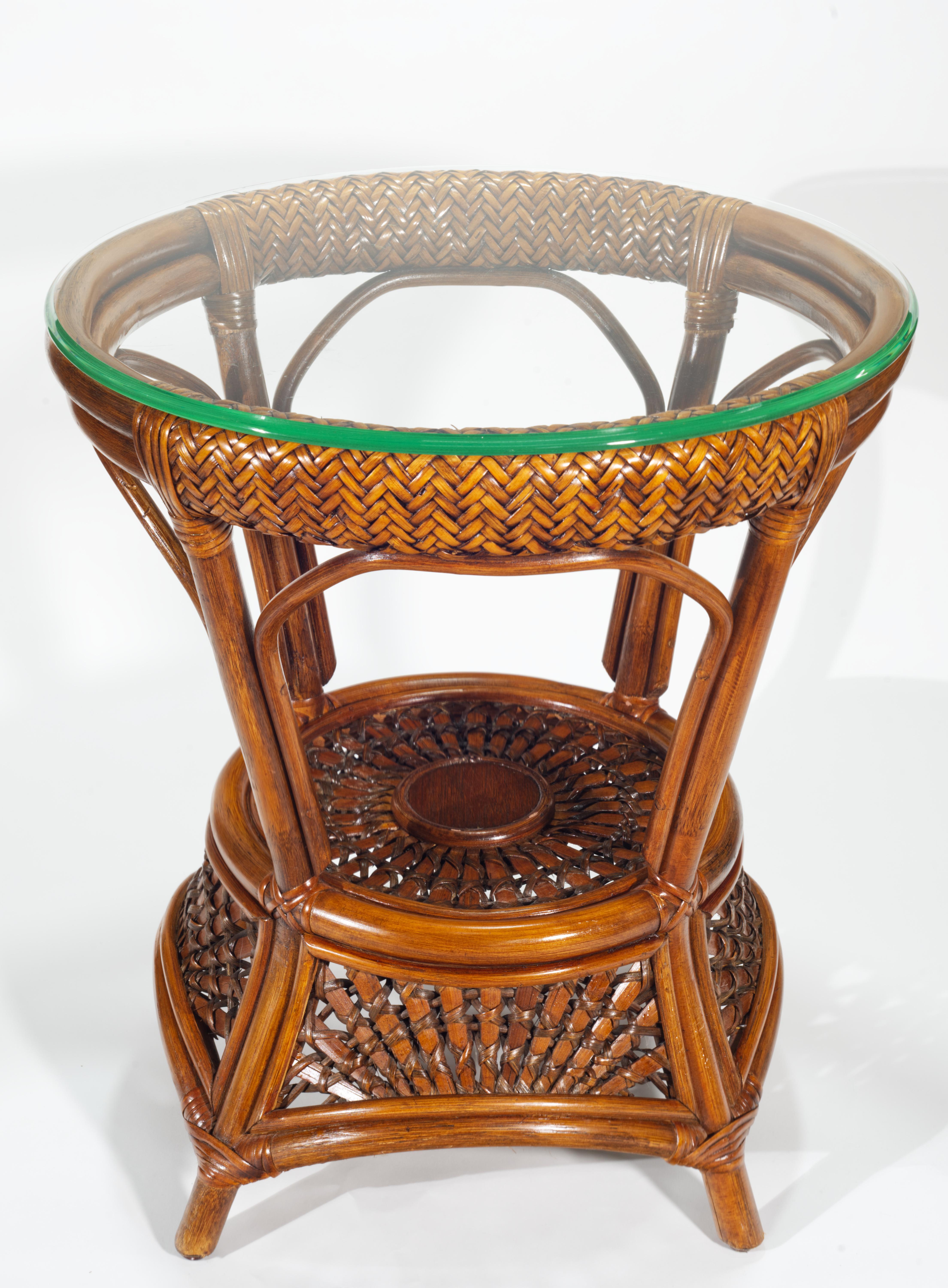  Vintage rattan and wicker side table features elegant two-tier design with the glass top and woven lower shelf; the complex weave of the shelf continues down towards the floor, creating a charming skirt-like decor element and juxtaposing the