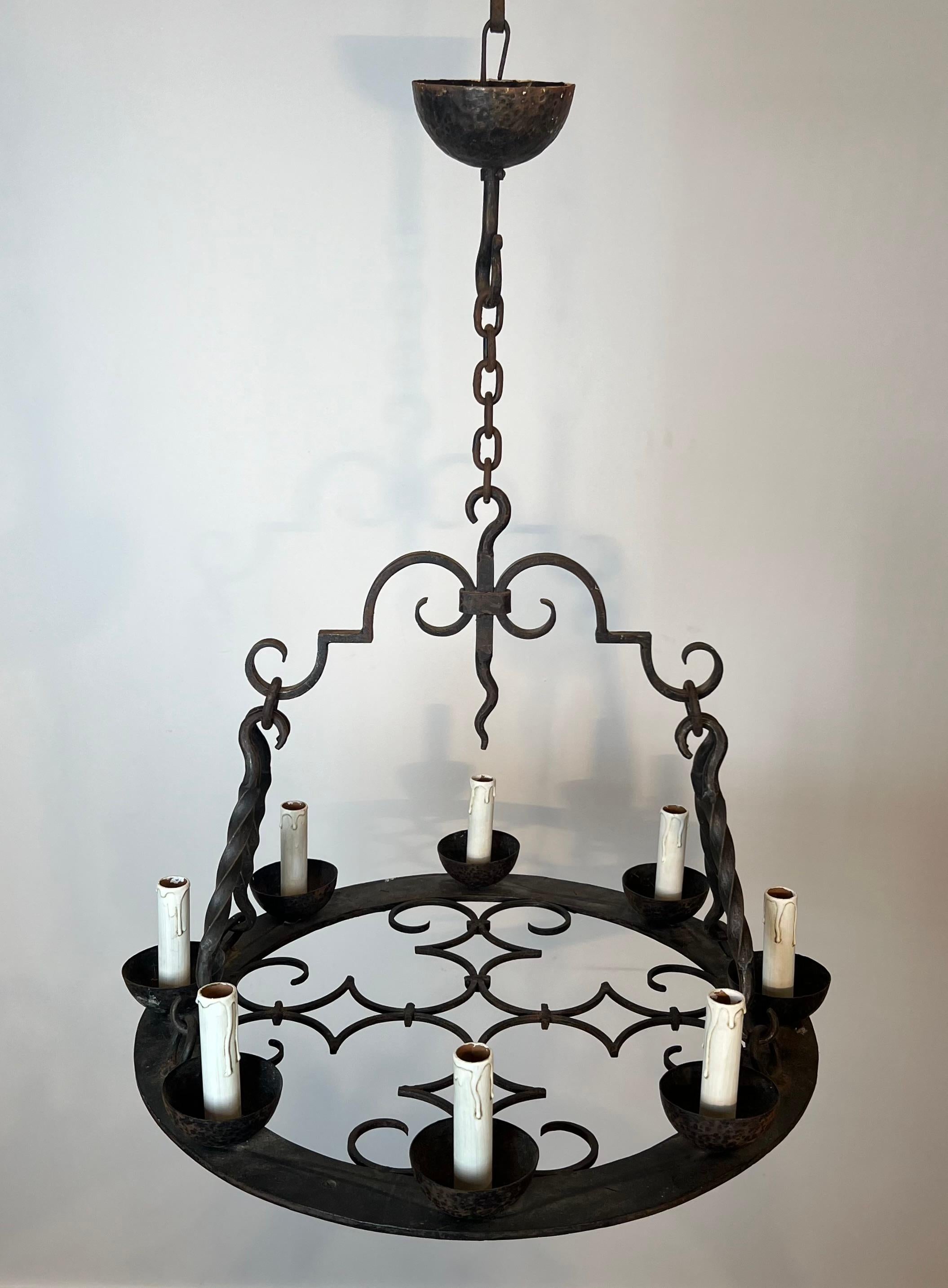 Questo lampadario rotondo a 8 luci è realizzato in ferro battuto. Si tratta di un'opera francese in stile gotico. Circa 1950