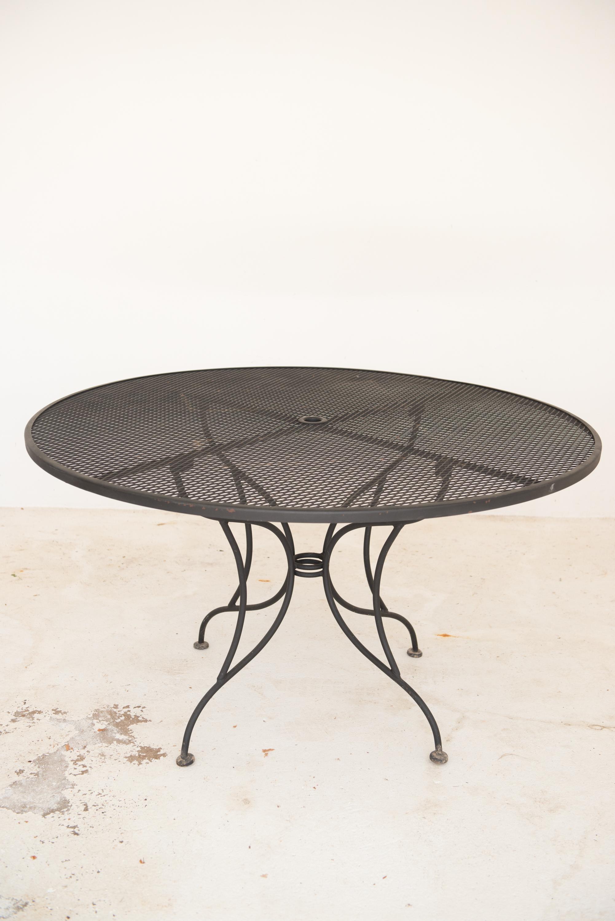 Mid Century Modern Woodard wrought iron and a practical metal mesh top dining table. Diameter is 53.5