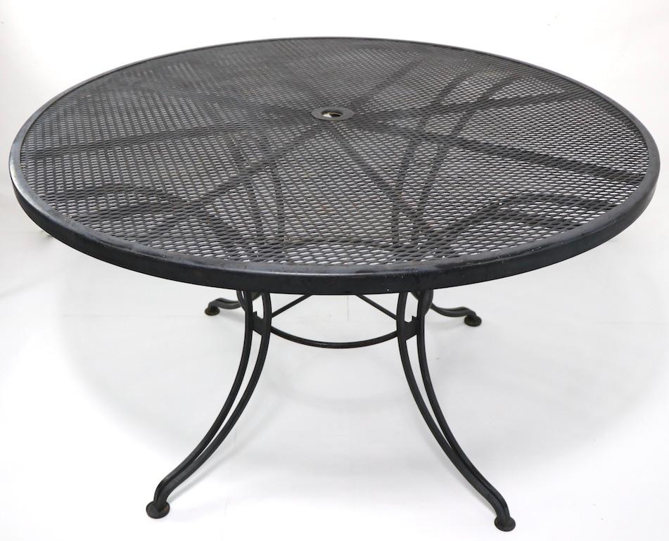 Wrought iron patio, garden table having a metal mesh top, on waisted from wrought iron base. The table is in very good, original clean condition, it has a 1.5 inch dia. hole in the center to accommodate a sun umbrella. The table easily disassembles