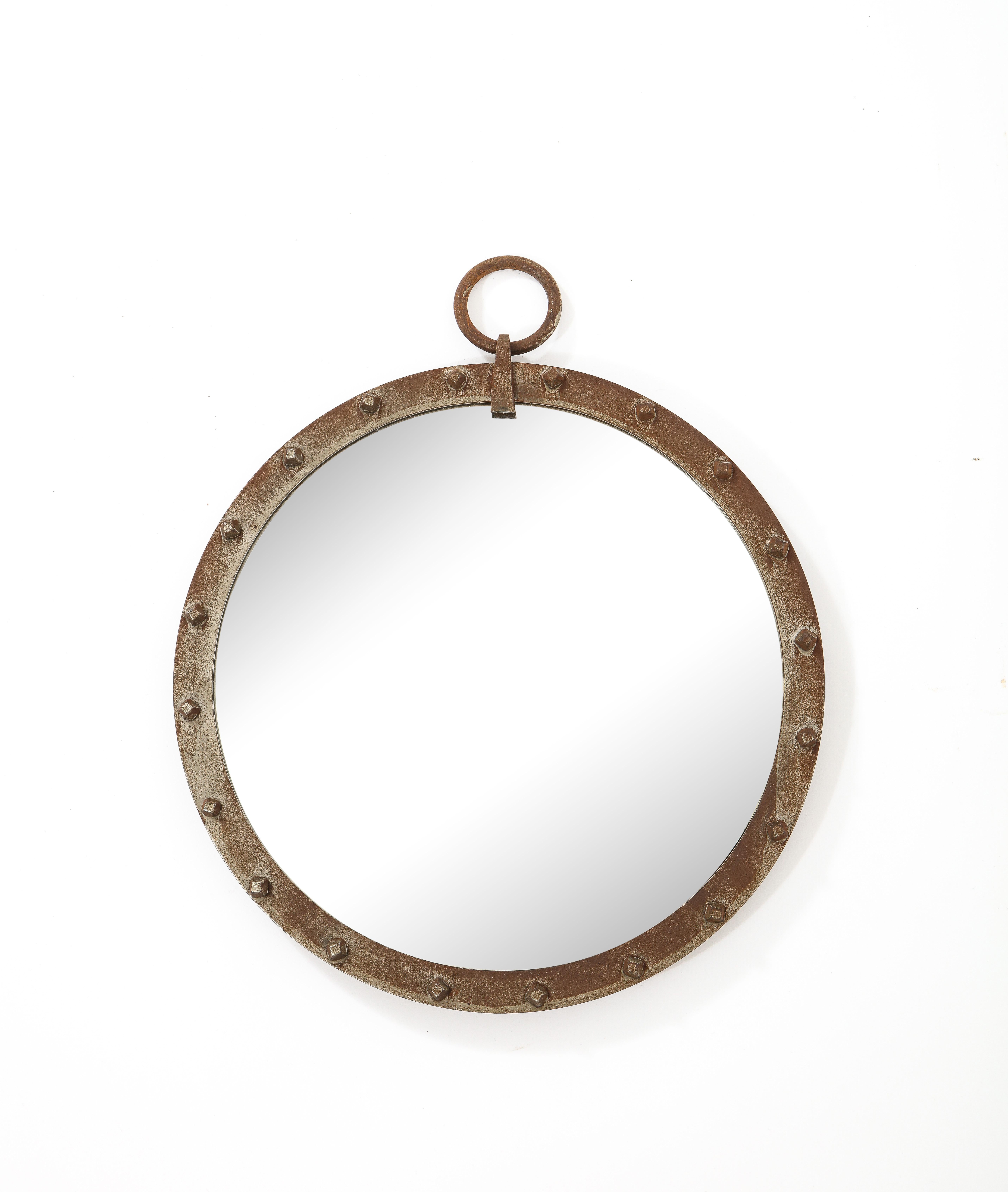 A minimal porthole mirror in a steel or wrought iron round frame hung by a ring. Cool detailing and patina.