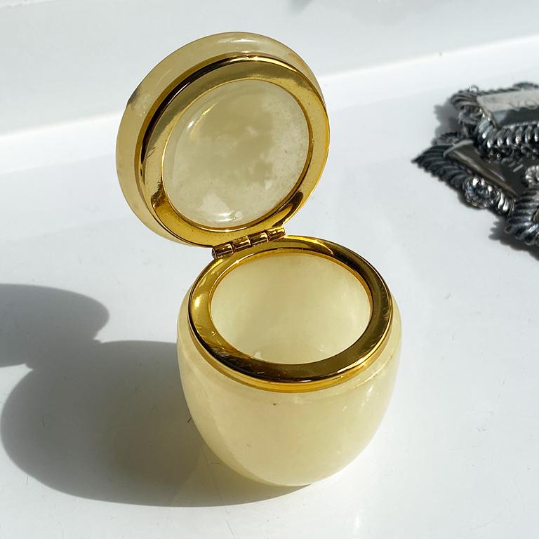 A beautiful round yellow alabaster trinket box. This small box has hinged a lid which is decorated with a gold metal rim at the lip. A floral design decorates the top. Great for dressing table or nightstand. 

Dimensions:
2