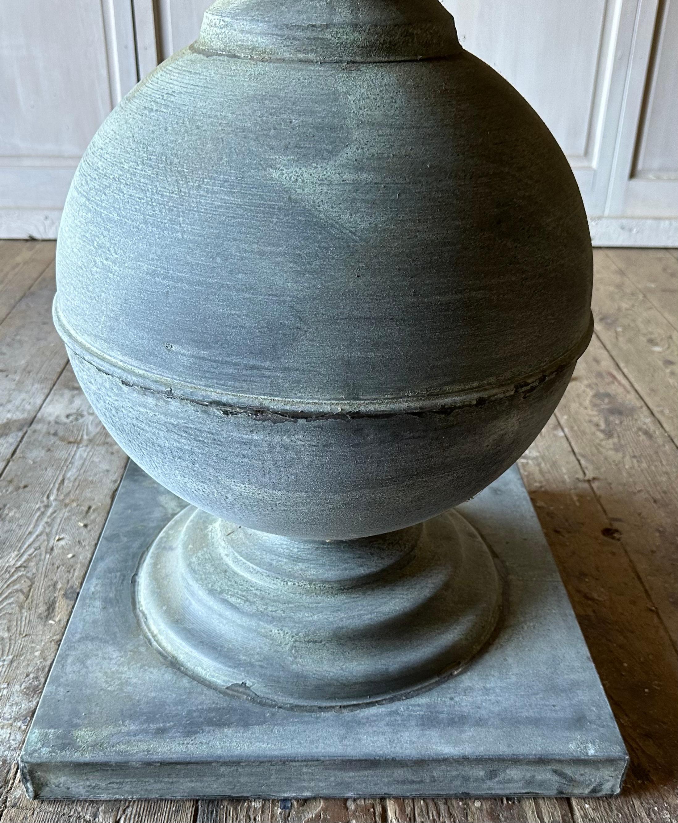 Splendido tavolo rotondo con piedistallo rivestito in zinco della fine del XX secolo con una bella patina invecchiata, piedistallo a forma di palla esagerata per stile e carattere. Il piano del tavolo è nuovo, la base in zinco risale alla fine del