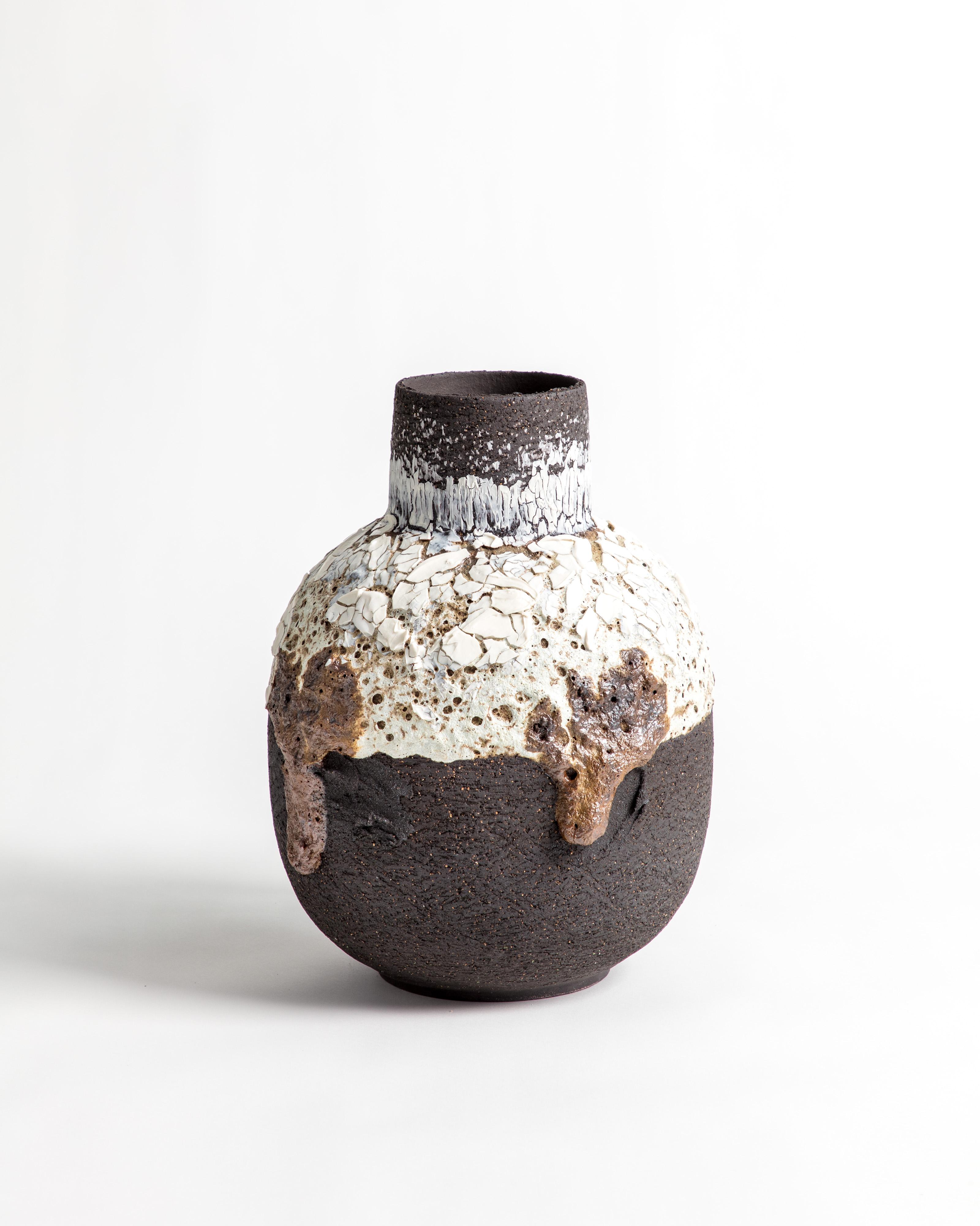An individual Rounded black, white and brown volcanic vessel with added lava stone.

Inspiration for the piece comes from the clay itself and the chemical relationships that glaze and volcanic matter create. Travels around the world, particularly