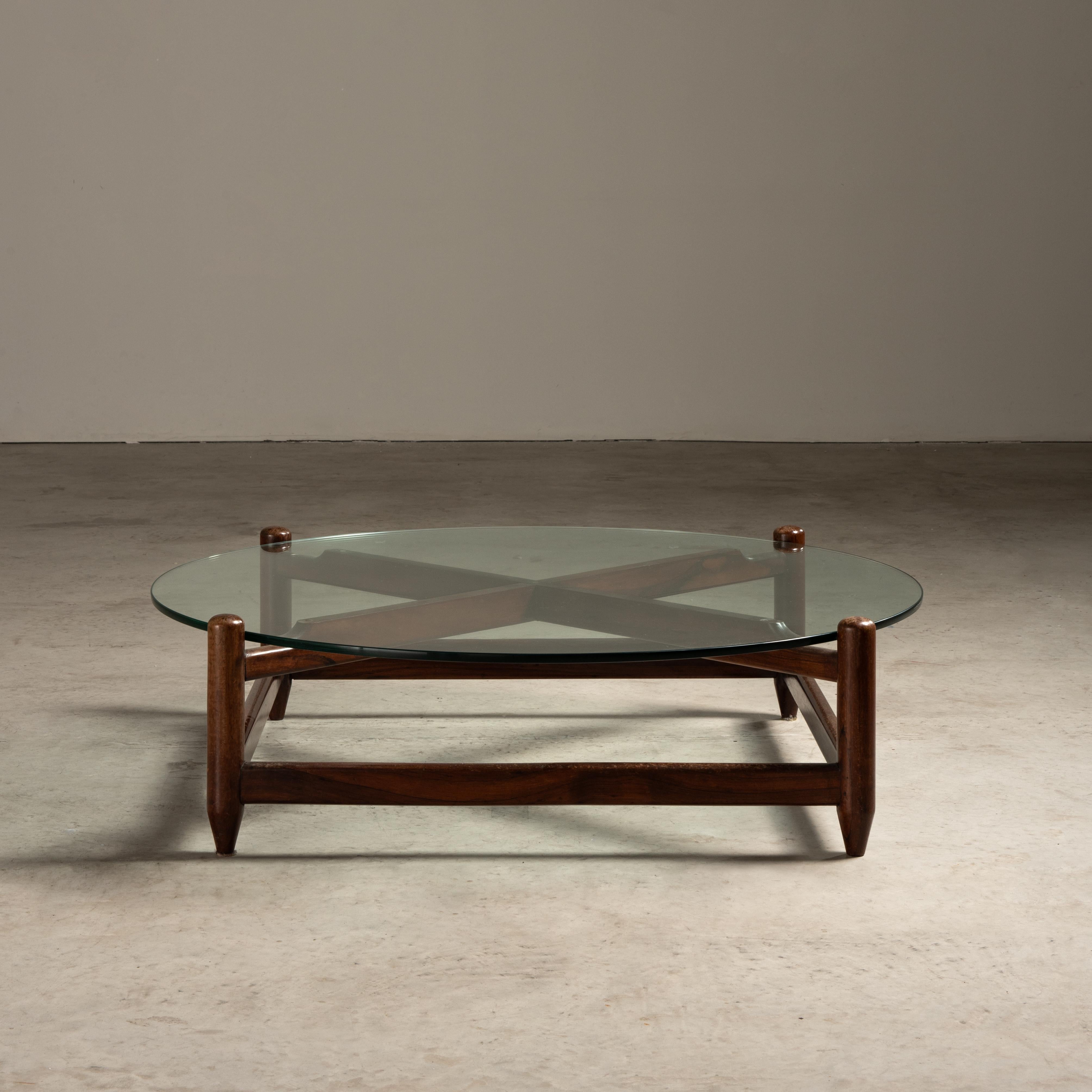 Esta mesa de centro de Móveis Cantu, hecha con madera y cristal, es un buen ejemplo del diseño brasileño de mediados de siglo. La mesa tiene un tablero circular de cristal que se asienta cómodamente sobre una base de madera. La base está hecha de