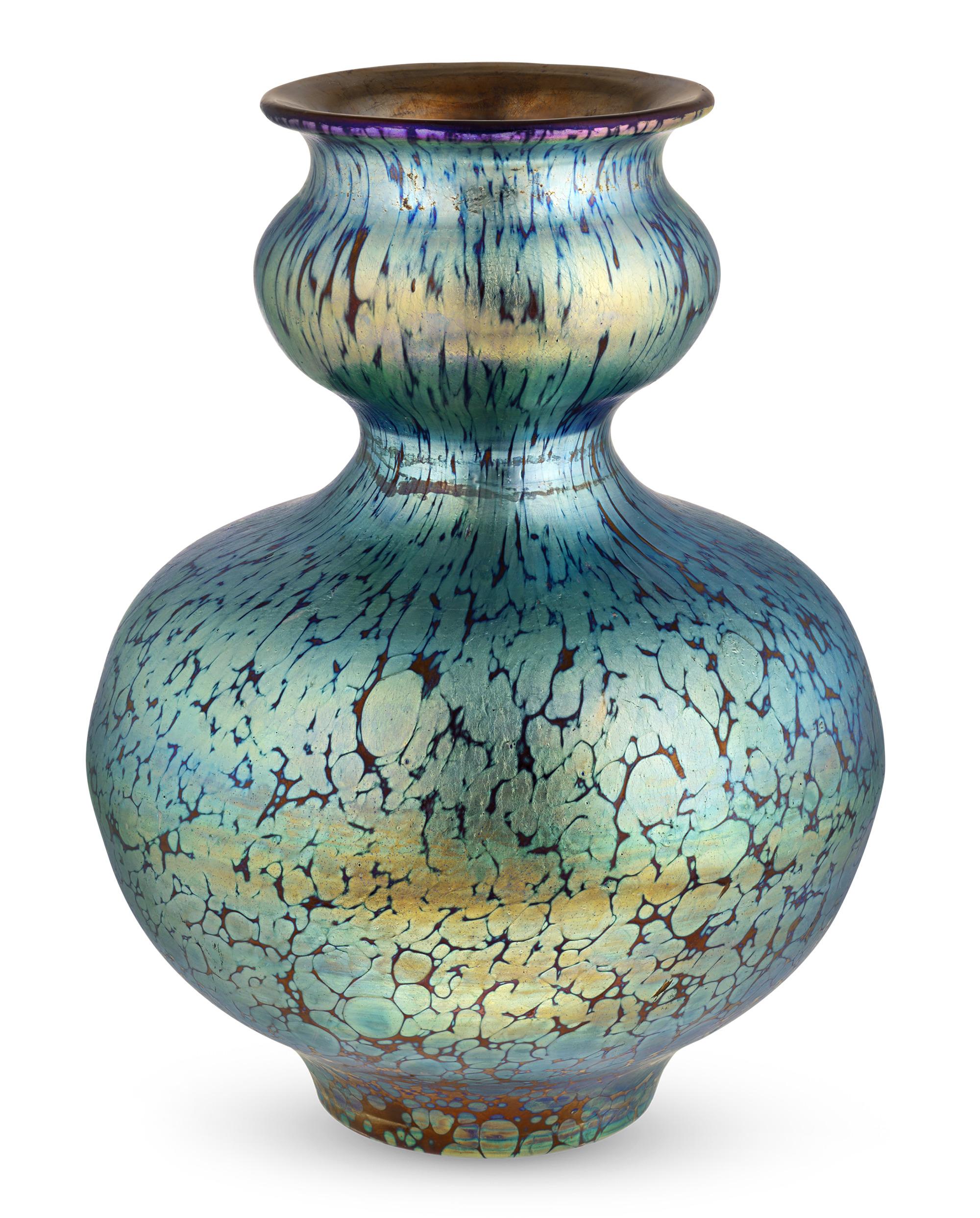 This exquisite vase belongs to Loetz's prestigious Papillon collection and is identified as the 7724 form. Renowned for its captivating color palette, this piece showcases a striking blend of blue, green and purple hues, producing an iridescent