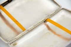 Rounded rectangular silver case with floral engravings on lid