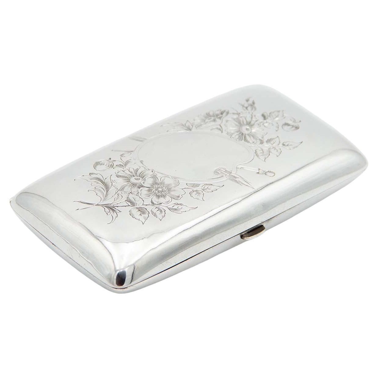 Rounded rectangular silver case with floral engravings on lid