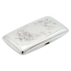 Rounded rectangular silver case with floral engravings on lid