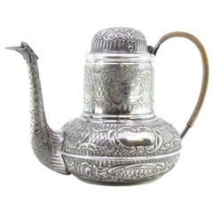 Rounded silver kettle w/ reliefs surrounding the monogram card
coated handle