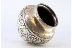 Rounded silver pot with raised floral motifs and friezes
