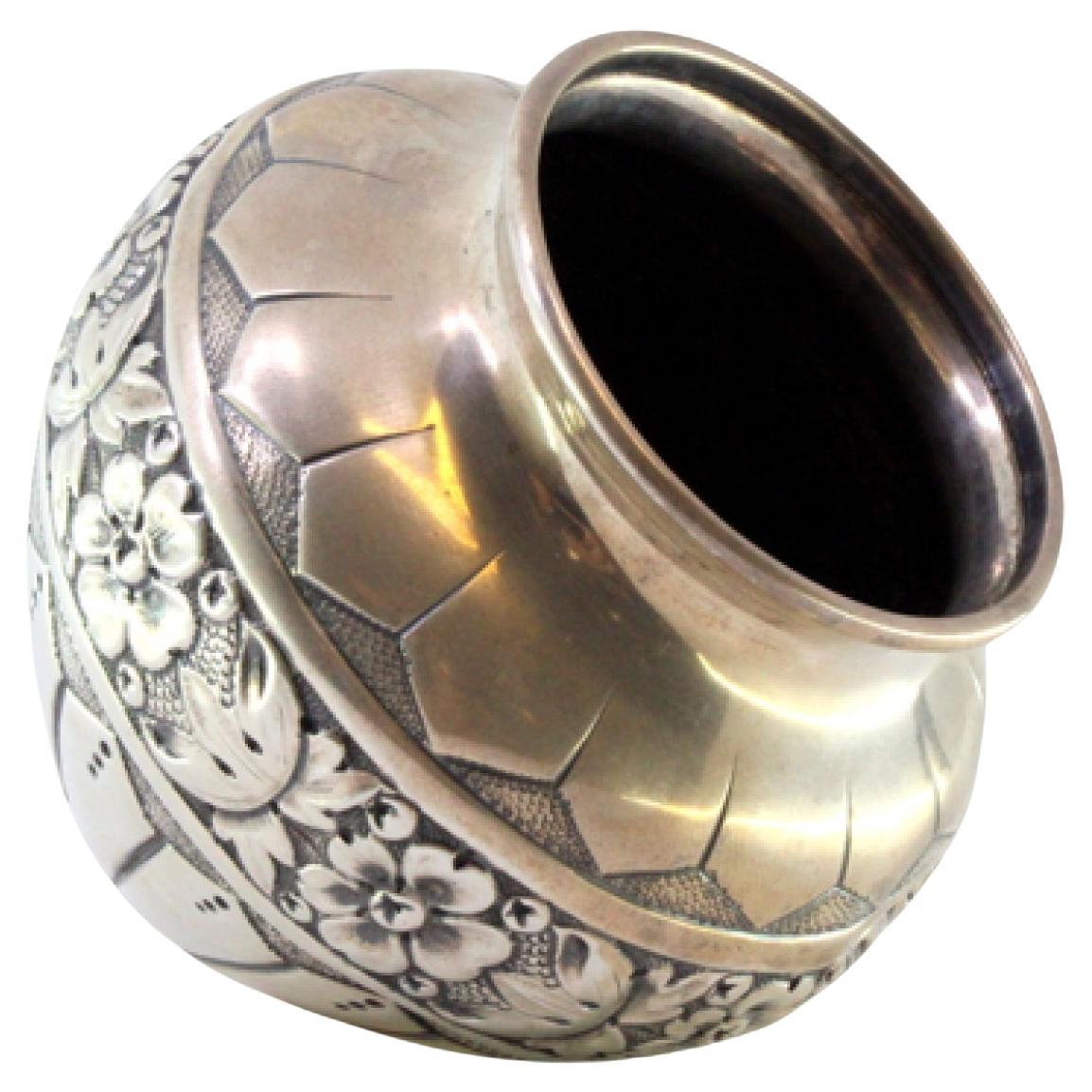 Rounded silver pot with raised floral motifs and friezes