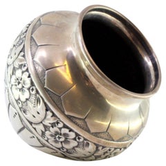 Rounded silver pot with raised floral motifs and friezes