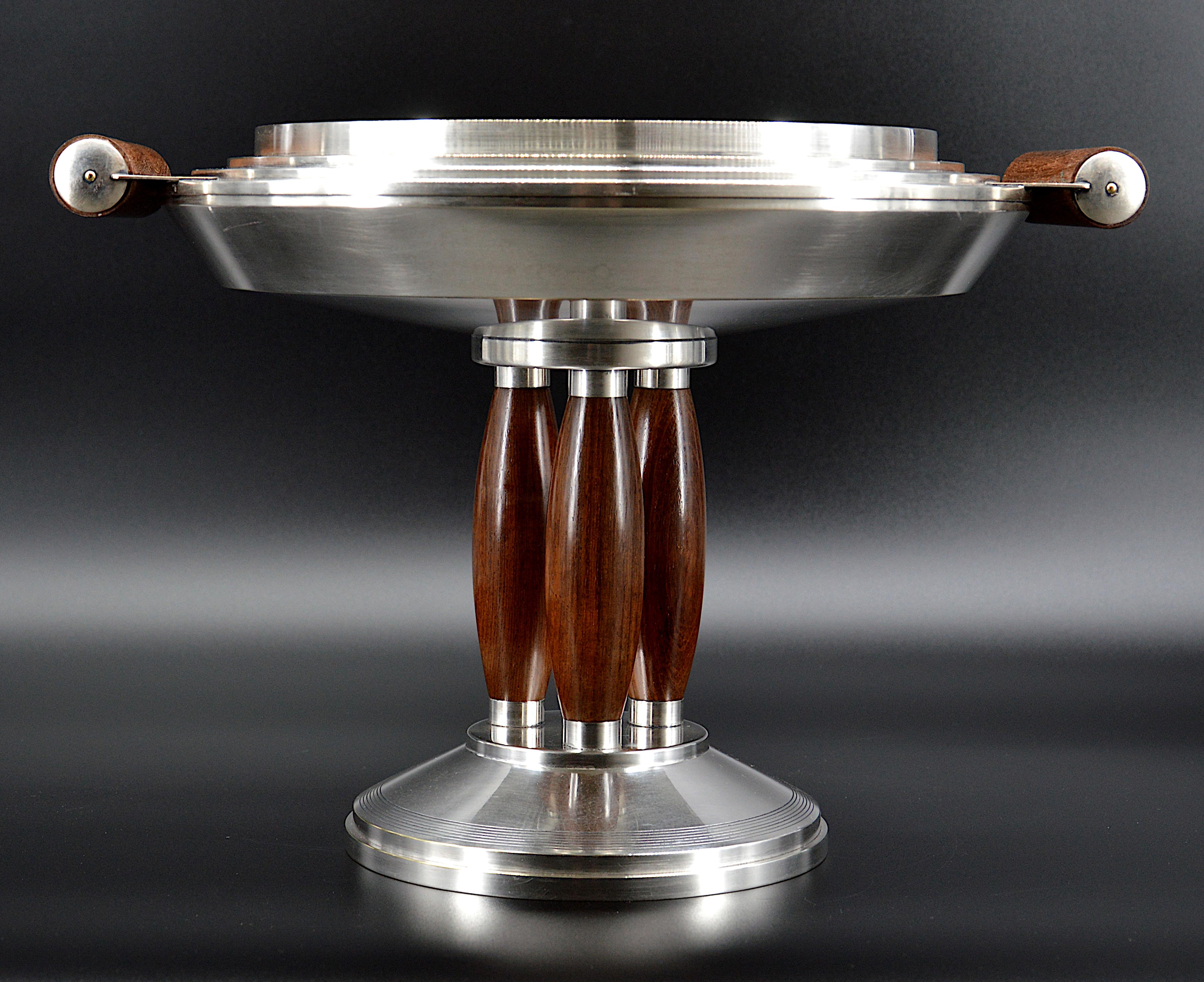 French Art Deco centerpiece by Roux-Marquiand, Lyon,, France, ca.1930. French Art Deco polished silver plate pedestal bowl. Centerpiece or fruit bowl. Art Deco design with three legs and two handles in wood. Round stepped bowl. Height: 11