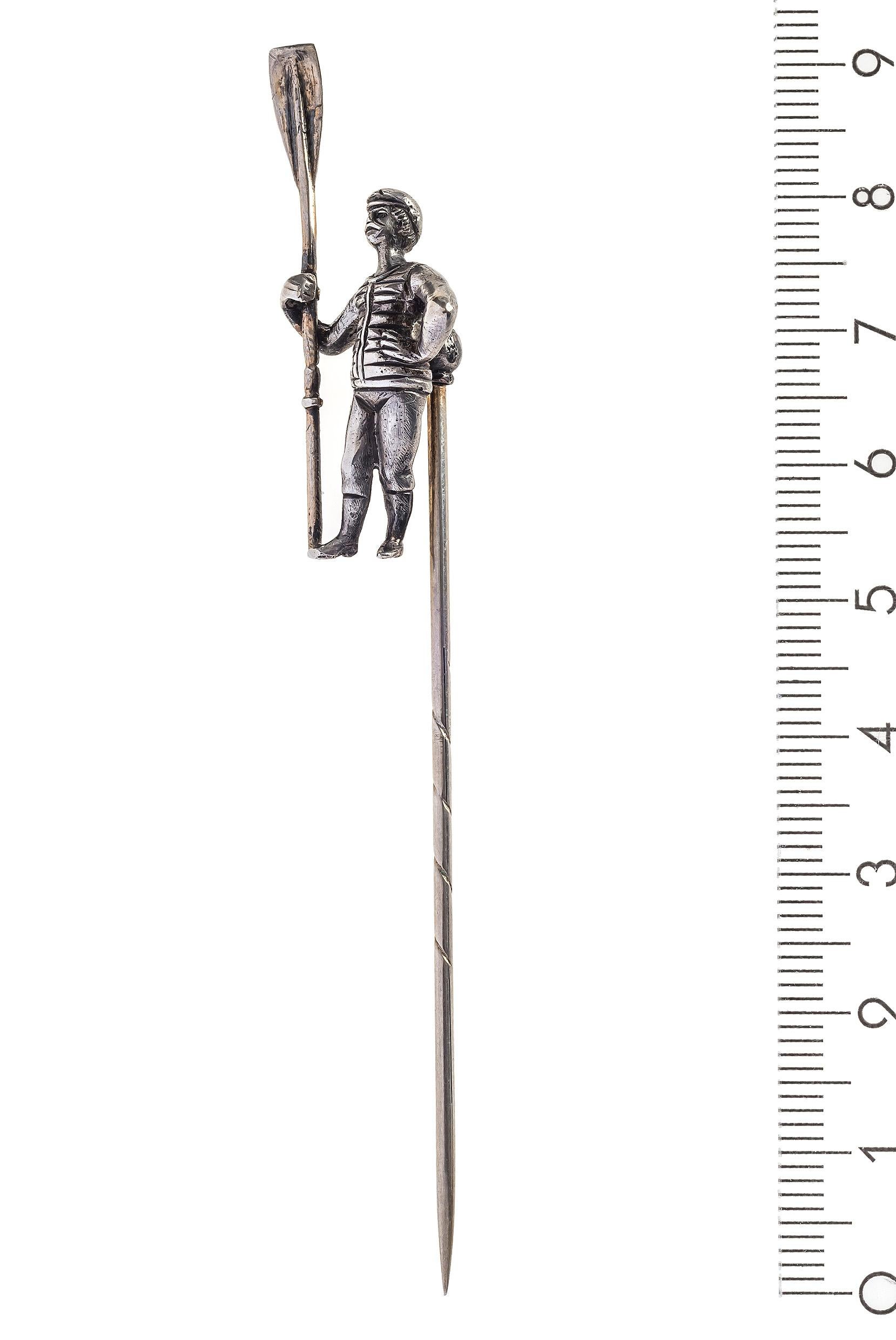 Unusual silver stick pin depicting a bearded rower with a flat cap, moustache, tricot, trousers and boots. He is holding an oar in his right hand. Traces of gilding on the oar and the stick pin. Unidentified makers mark. The pin is from the period