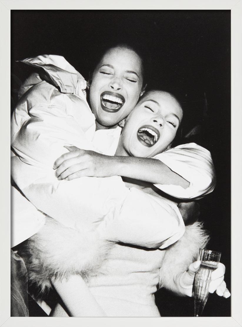 Un ritratto in bianco e nero delle due top model Christy Turlington e Kate Moss che ridono nel backstage della sfilata di Isaac Mizrahi del 1994, fotografate da Roxanne Lowit.

Tutte le stampe sono in edizione limitata. Disponibile in più misure.