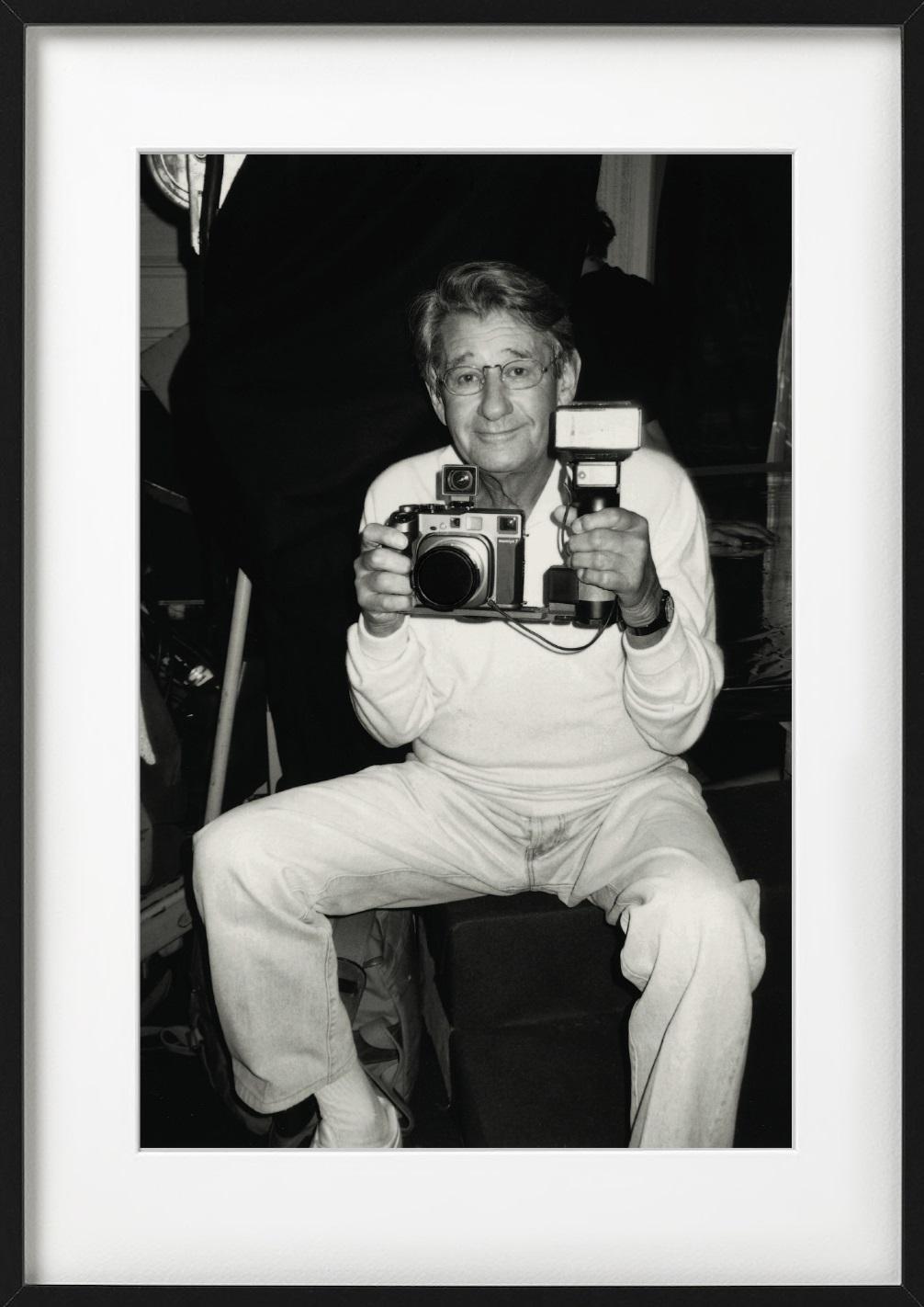 Helmut Newton, Paris - famous photographer holding a camera in b&w - Photograph by Roxanne Lowit