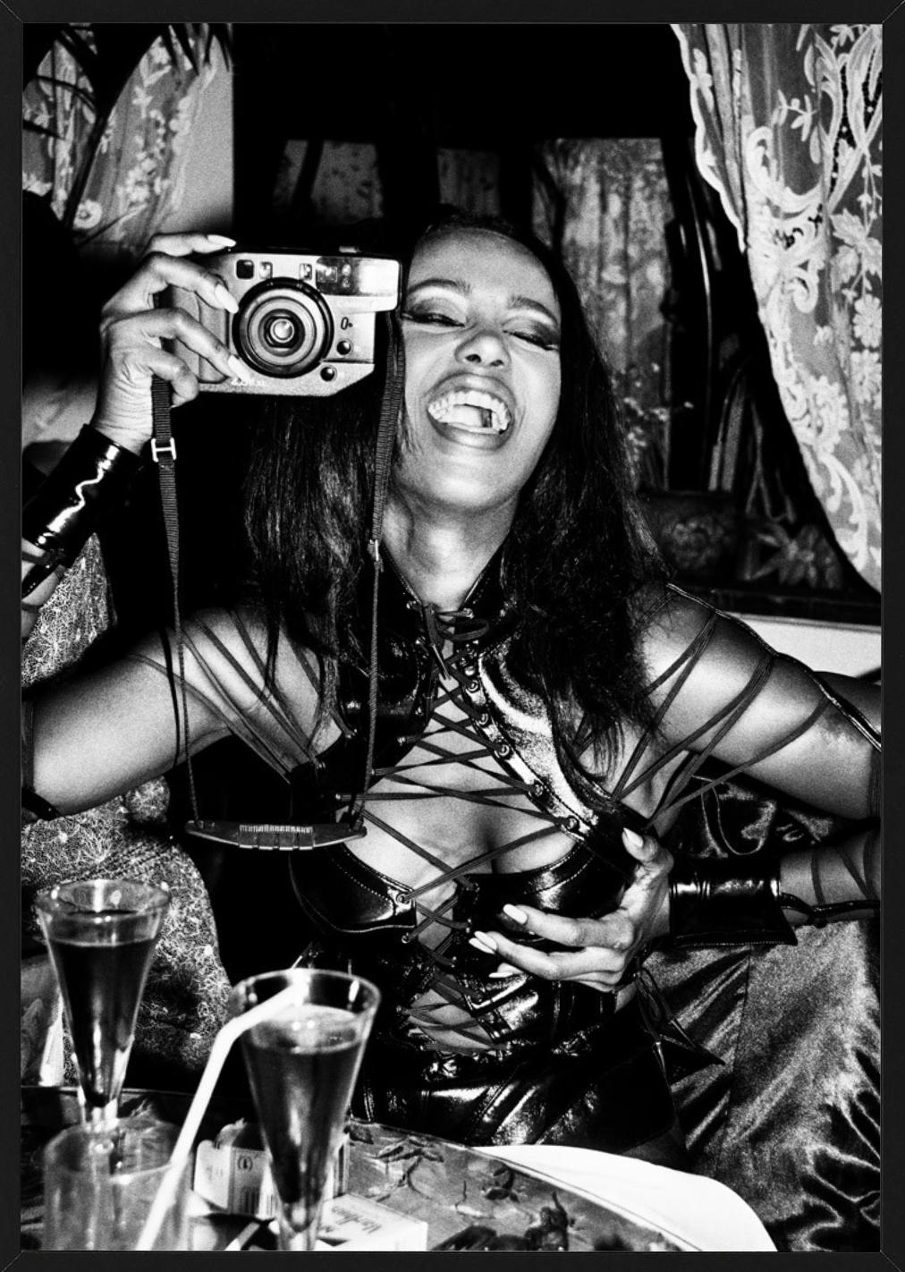 Iman, Paris - black-and-white portrait of model Iman in corsage with camera  - Contemporary Photograph by Roxanne Lowit