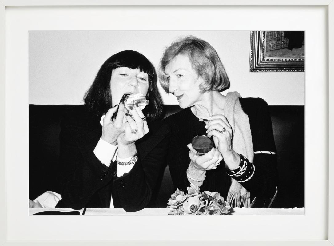 La famosa artista June Newton e la stilista Andrée Putman siedono insieme al ristorante Les Bouchons di Parigi e si riapplicano il rossetto. Fotografato da Roxanne Lowit nel 1981.

Tutte le stampe sono in edizione limitata. Disponibile in più