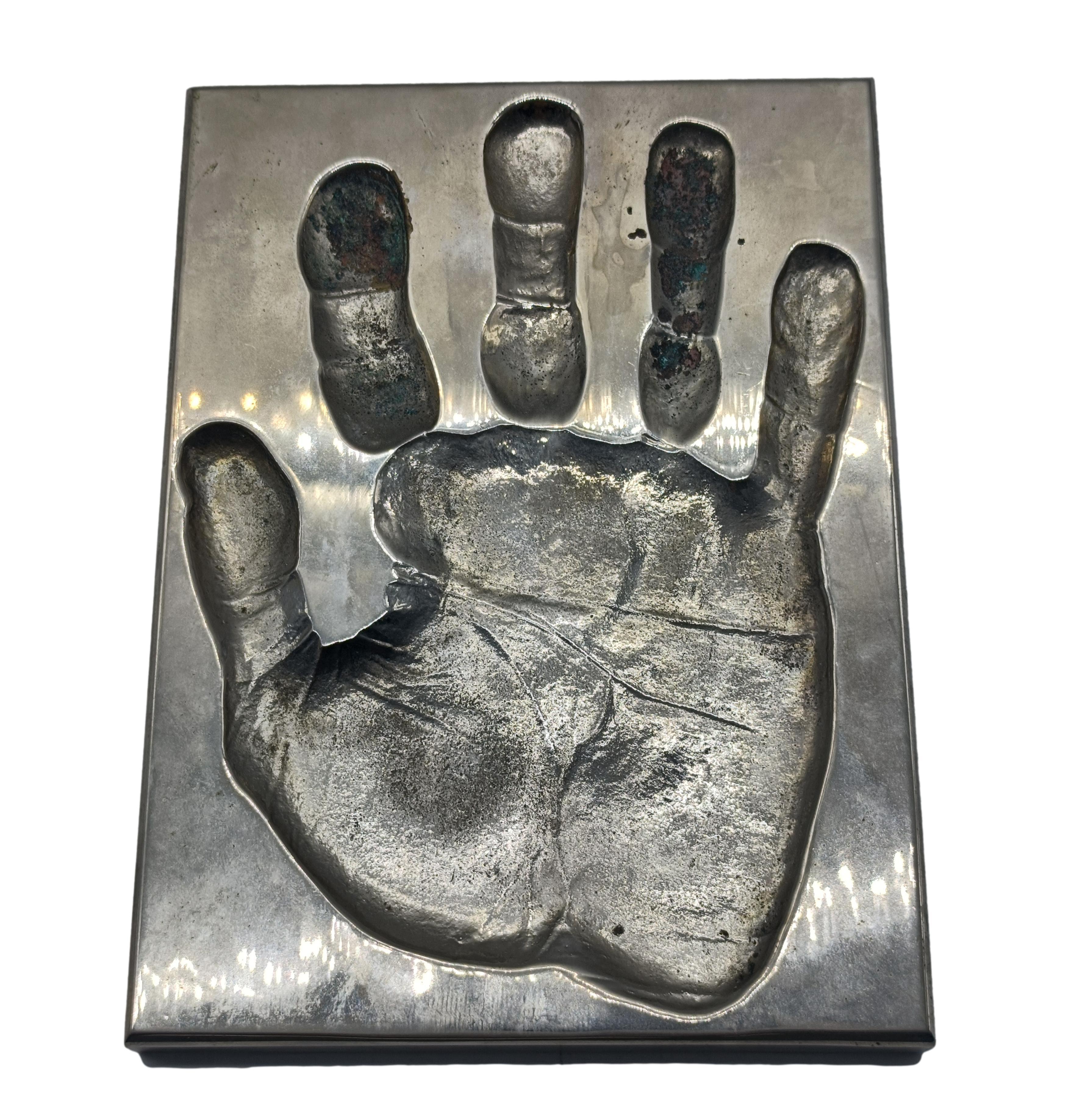 Scultura da tavolo in alluminio pressofuso raffigurante il palmo di una mano, attribuita all'Artista Roy Adzak.
Nato a Royston Stanley Wright, Roy Adzak è stato un artista che ha lavorato principalmente con la scultura, la fotografia, l'incisione e