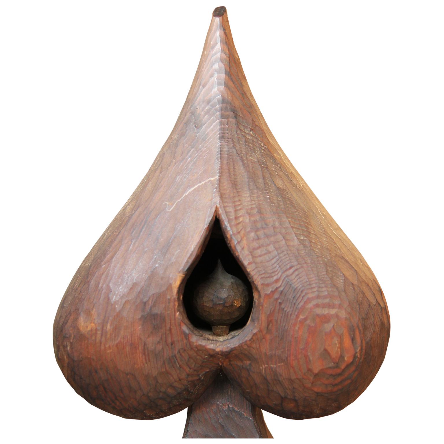 Modern surrealist abstract wooden sculpture by Texas artist Roy Fridge. The work features a prominent spade shape with two open recesses. The top opening exposes a teardrop shape and the bottom shows more machine-like forms. Currently mounted onto a