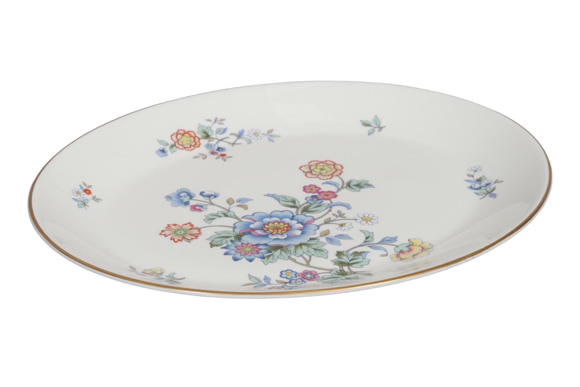 An English Bone China serving platter, produced by Royal Albert in the 1980's in their Hidden Valley, New Romance pattern. An off-center bouquet of stylized flowers is mirrored in floral sprays around the gilt-edged lip. Maker's mark underneath.