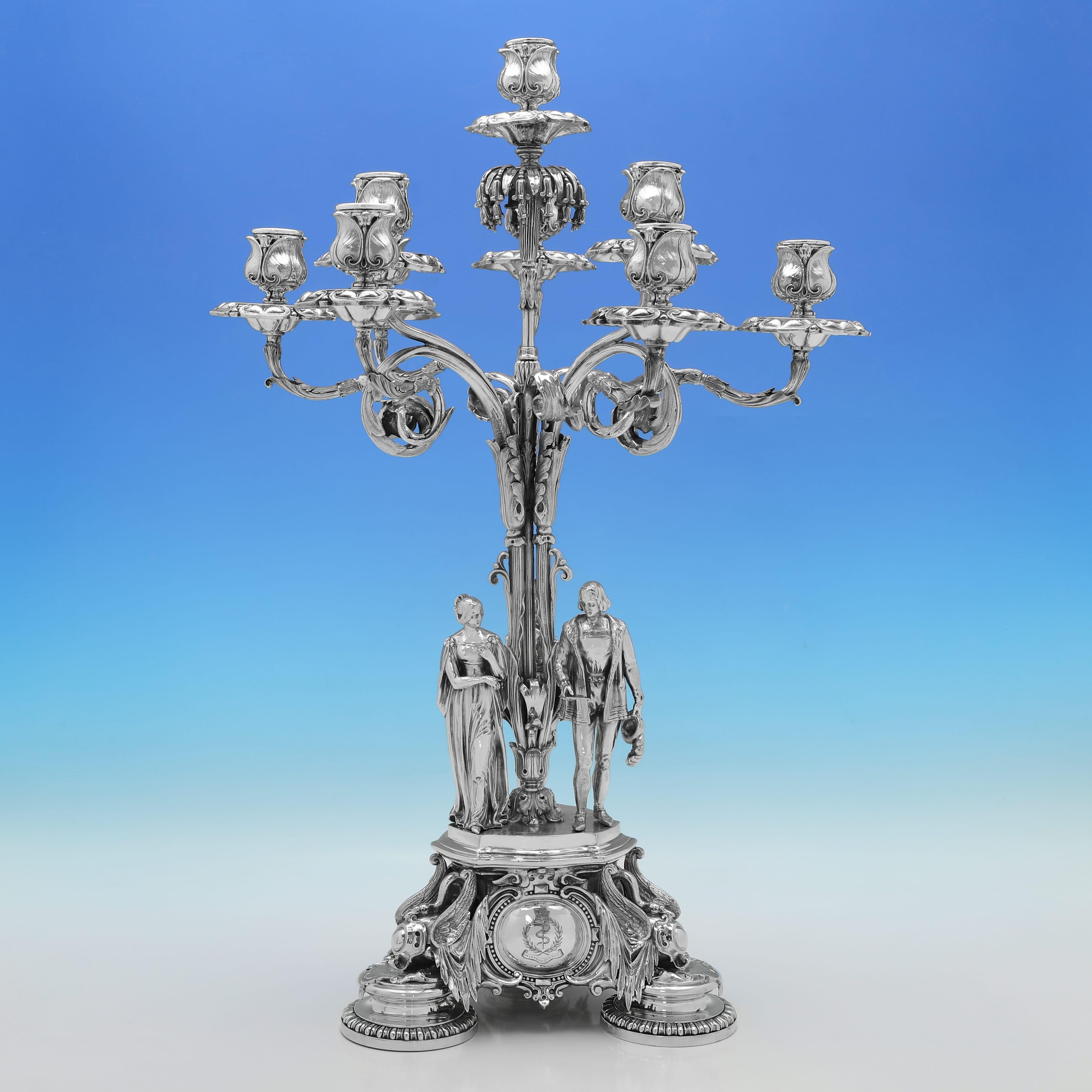 Fabriquée vers 1855 par Elkington, Mason & Co, cette superbe paire de grands chandeliers anciens en métal argenté de l'époque victorienne peut contenir 9 bougies chacun et présente des sculptures figuratives à la base, ainsi que des détails