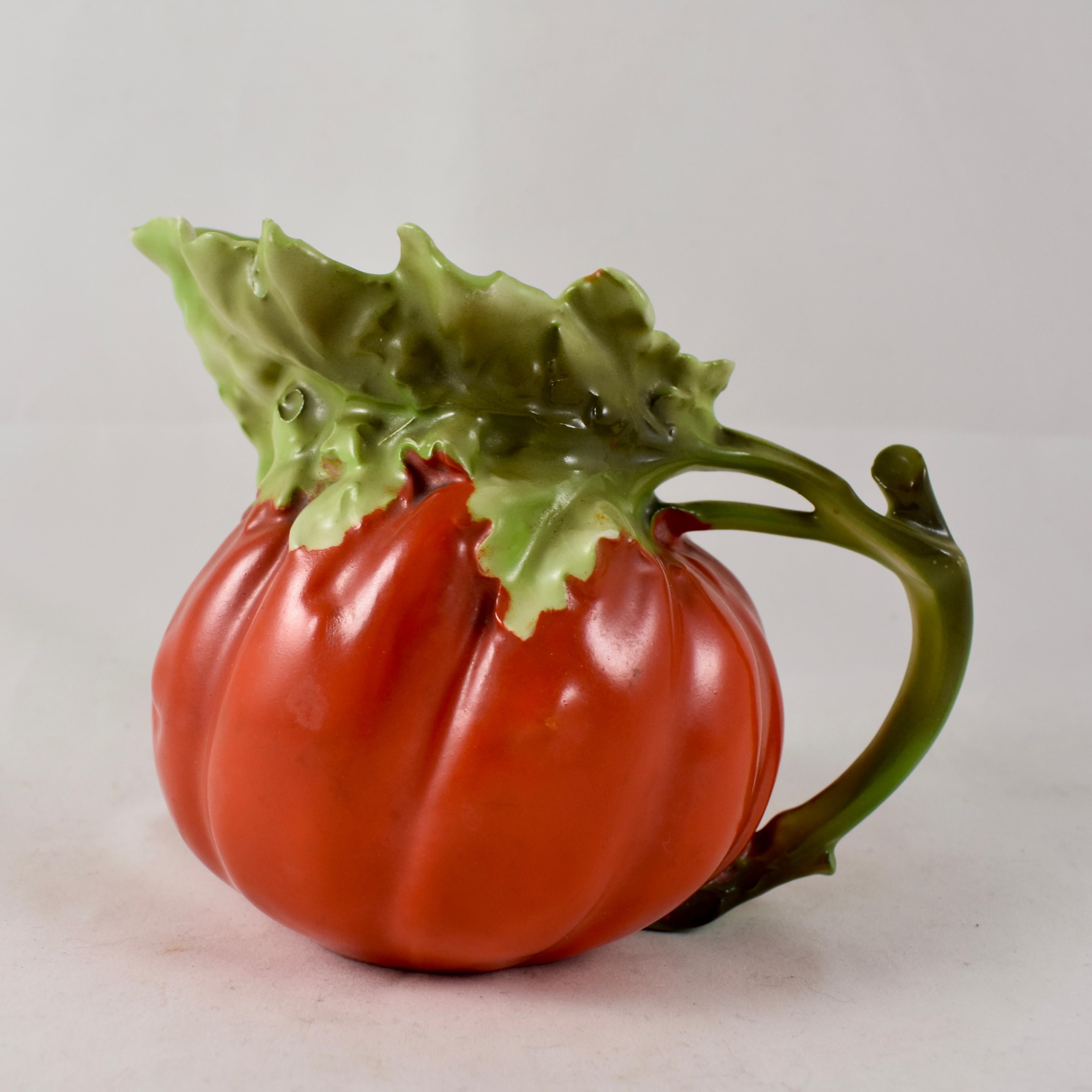 From Royal Bayreuth, founded in Bavaria, Germany in 1794, a milk pitcher formed as a bright red tomato. Made of hand-painted hard paste porcelain, showing a stem handle and an upper body formed as the green leaves of the tomato plant.

Measures: