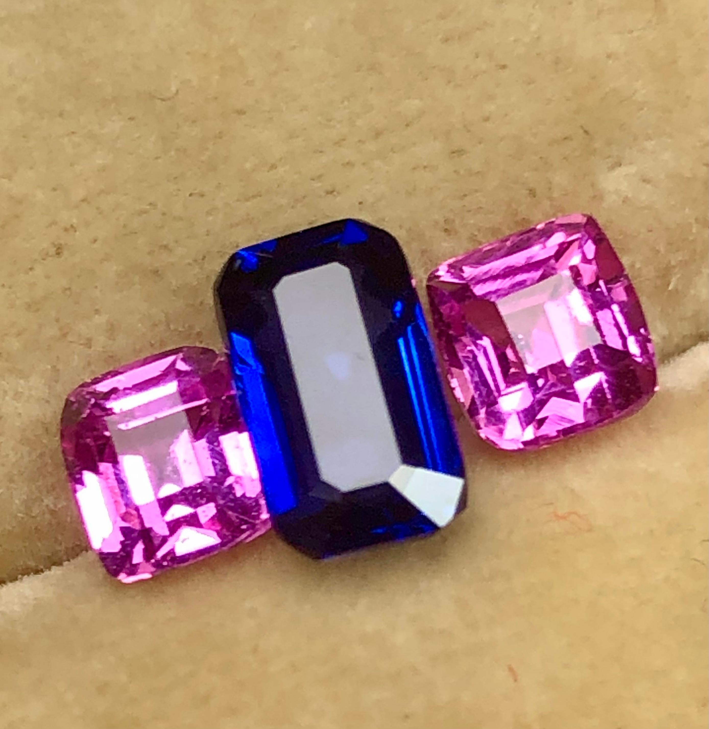 A center high-quality emerald cut royal blue Ceylon sapphire 1.30 carats and two vibrant, vivid pink Ceylon cushion cut sapphires weighing 1.60 carats. 
The trio of sapphires is of extremely fine quality and clarity, with excellent cutting