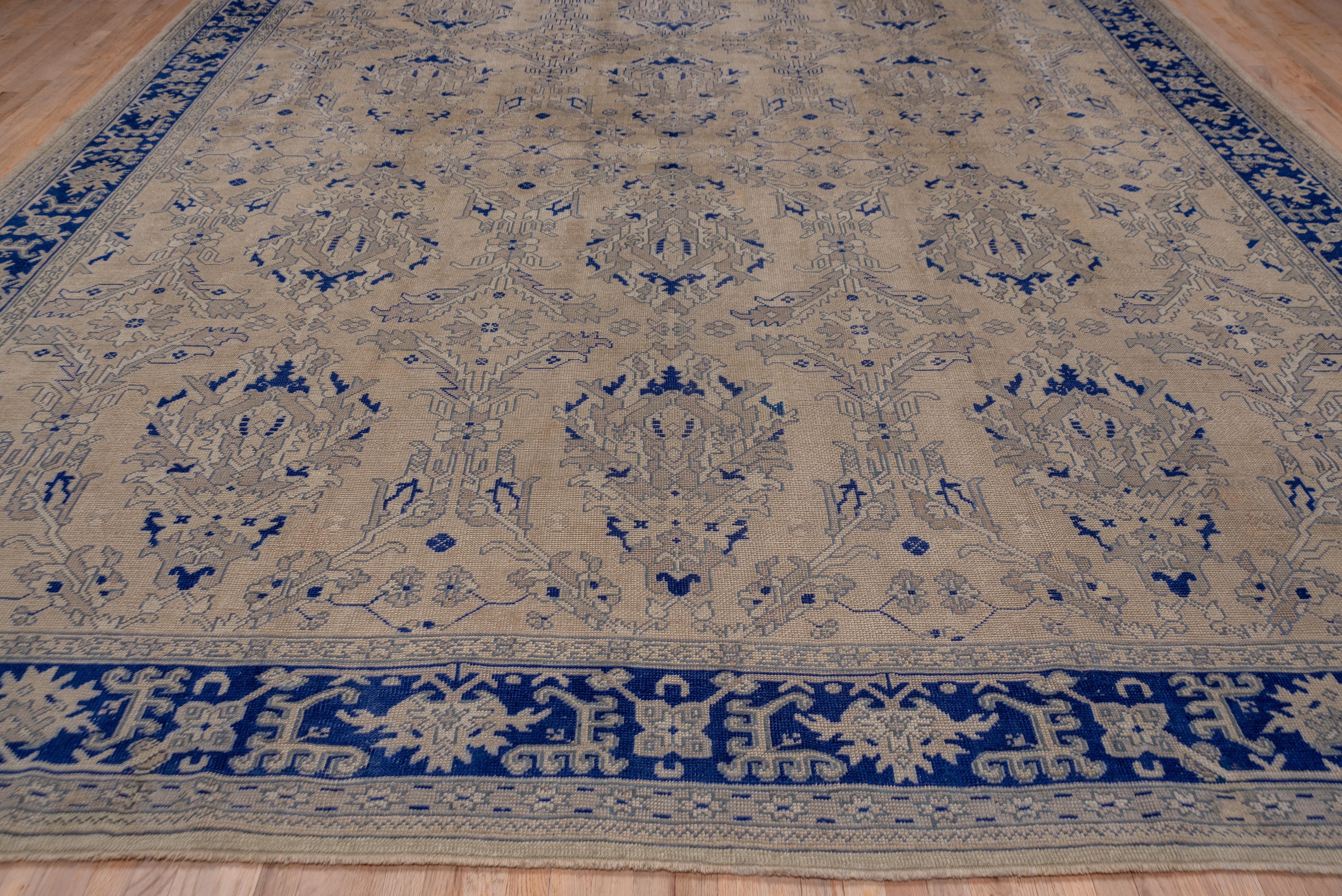 This straw field west Anatolian carpet has seven columns of jagged palmettes and Yaprak open diamonds. The drawing is particularly sharp and angular. The dark blue border displays ragged palmettes and sharply angled hooked leaves