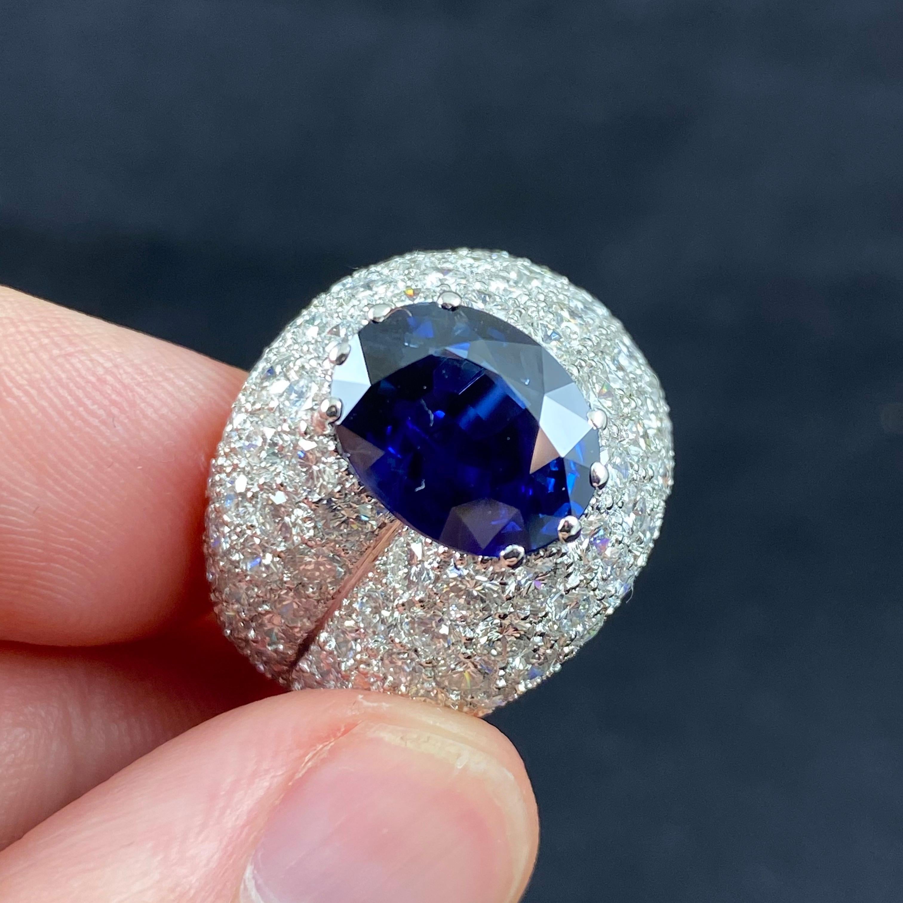 A contemporary royal blue Ceylon sapphire and diamond cocktail or dress ring in 19.2kt white gold, Portugal, 2010s. This ring features a 4.60ct oval mixed-cut sapphire of a vivid royal blue color claw-set to the centre, surrounded by a sea of