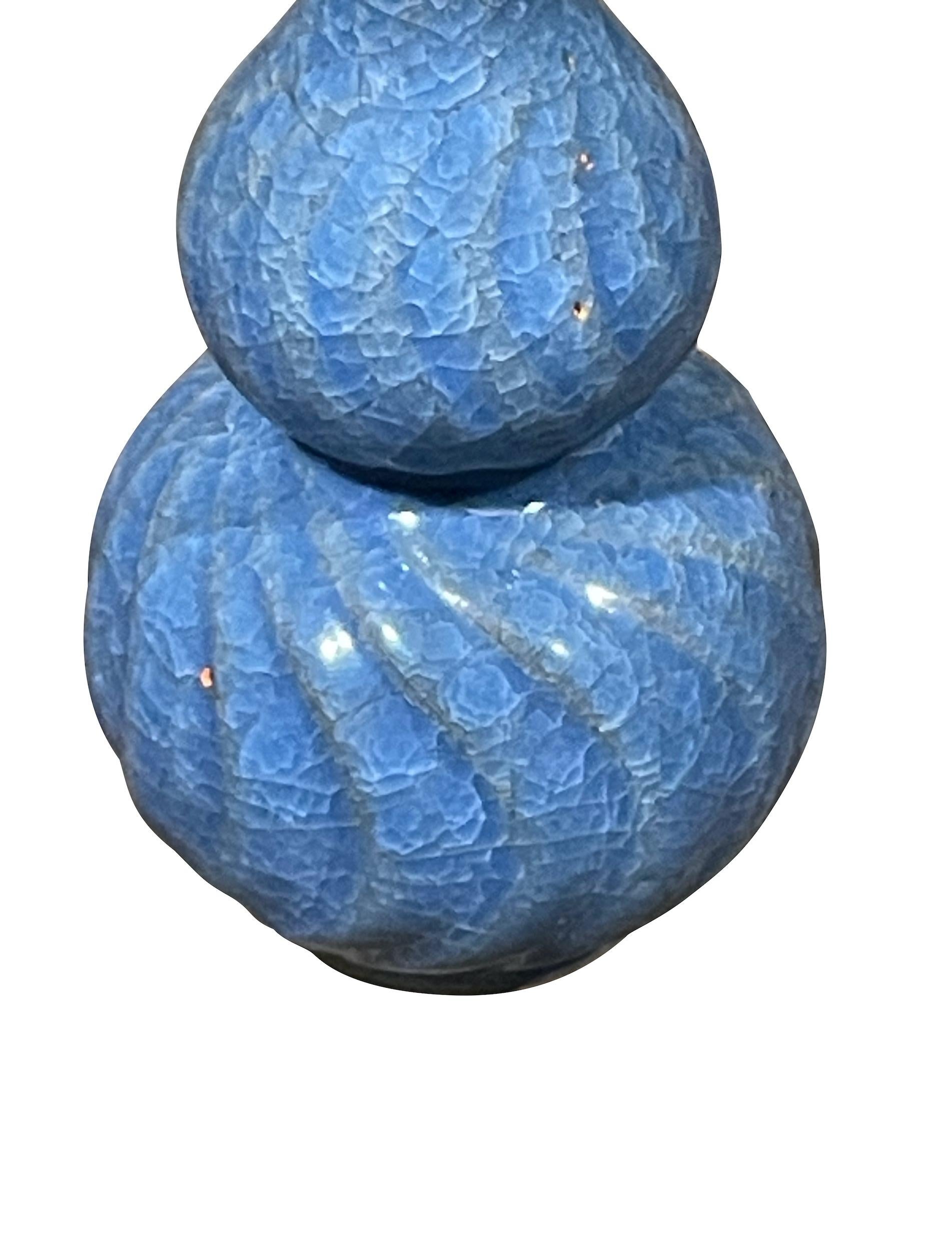 Vaso cinese contemporaneo di colore blu reale con smalto crepla.
Fa parte di un'ampia collezione di varie forme e dimensioni.
Forma a zucca con costola a spirale.