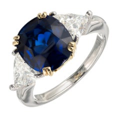 Anillo de compromiso de oro y platino con zafiro azul real en cojín y diamante