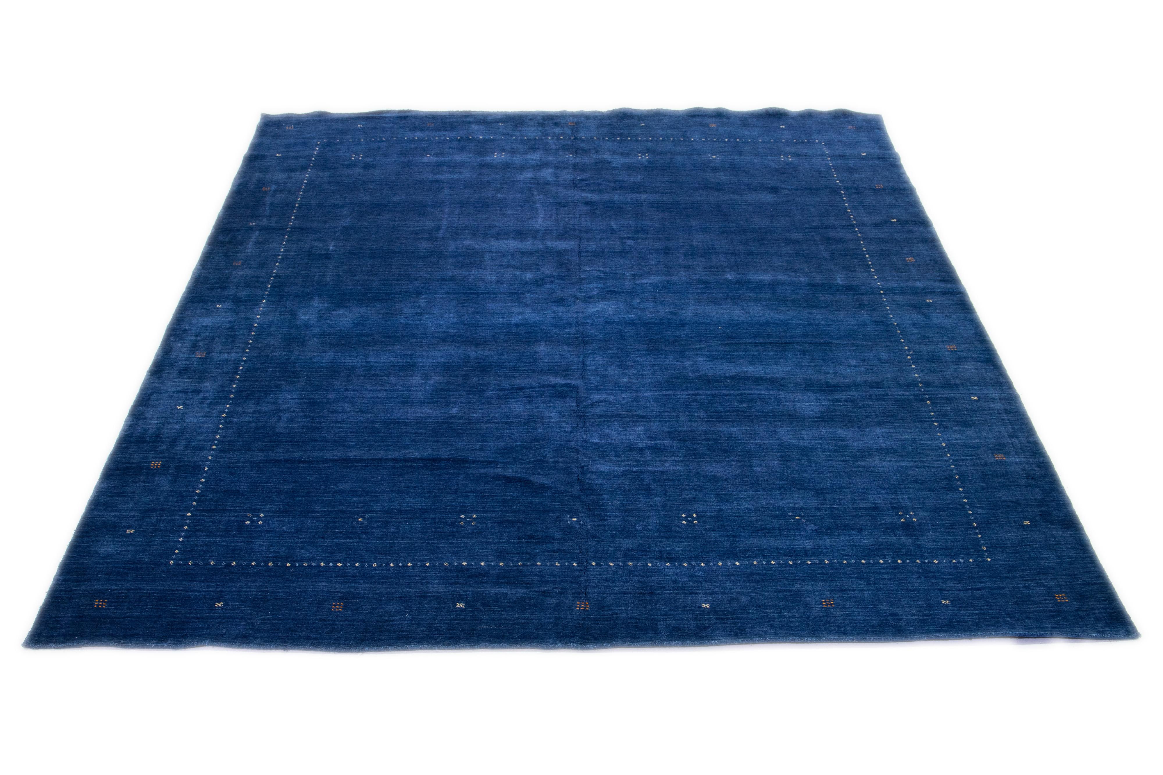 This modern Gabbeh rug, hand-loomed with exceptional care, embodies elegance and contemporary style with its minimalist geometric pattern. The alluring royal blue base is finely accented with orange details, establishing a refined presence within