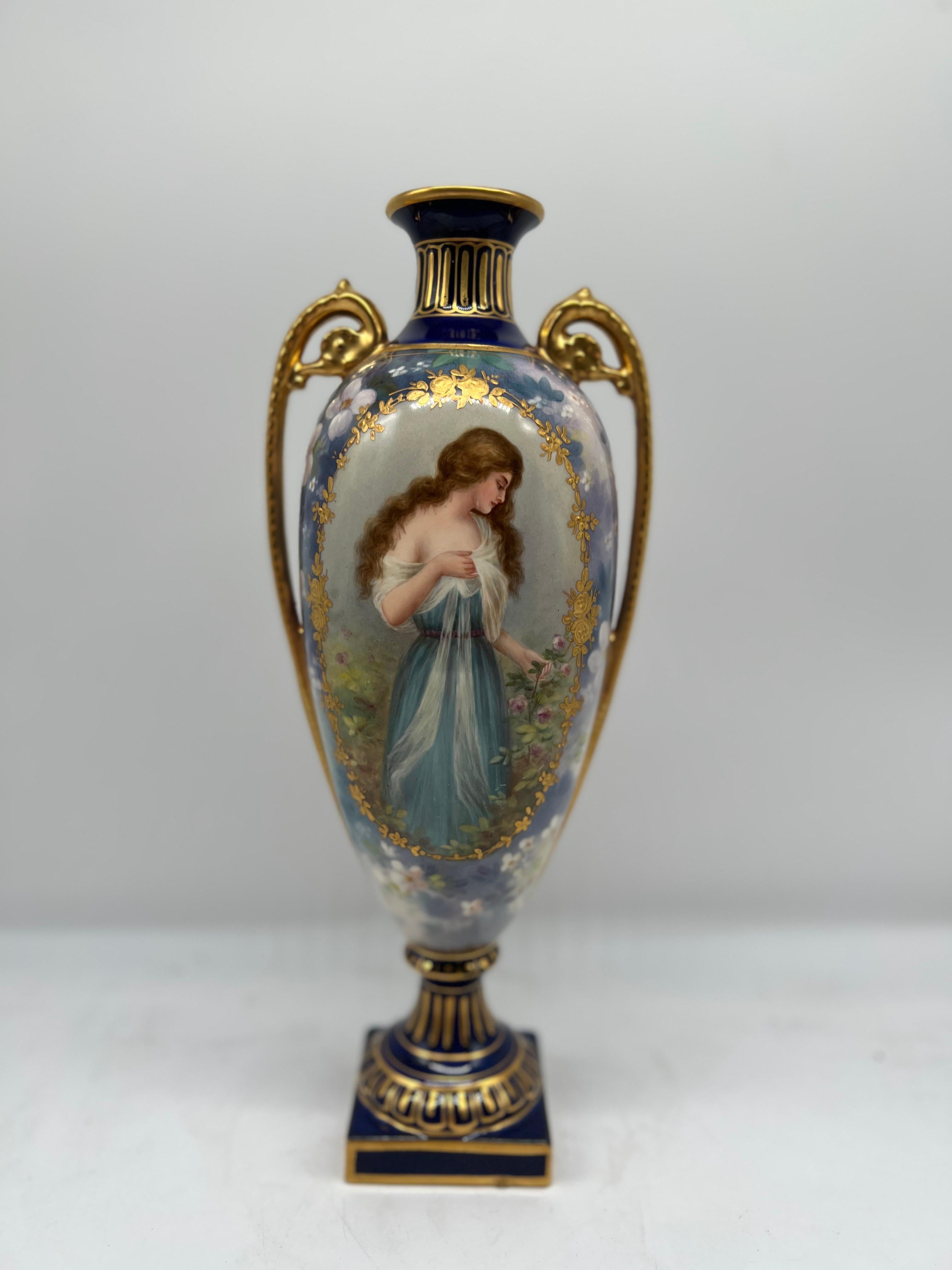Un antico vaso vittoriano dipinto Royal Bonn di Franz Anton Mehlem, realizzato a Bonn, in Germania.
Eleganza di una donna dipinta e drappeggiata in un abito blu. Foglie di alloro ornate in oro circondano la finestra centrale su una base blu cobalto
