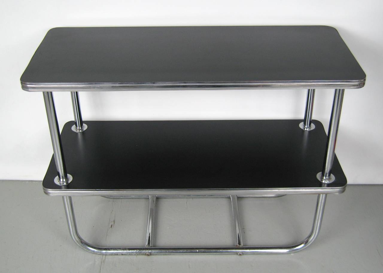 Stunning Art Deco tubular design on this table, sleek black color, rounded corners, double shelving. The chrome have some wear to the bottom rail as seen in the last photo.
   