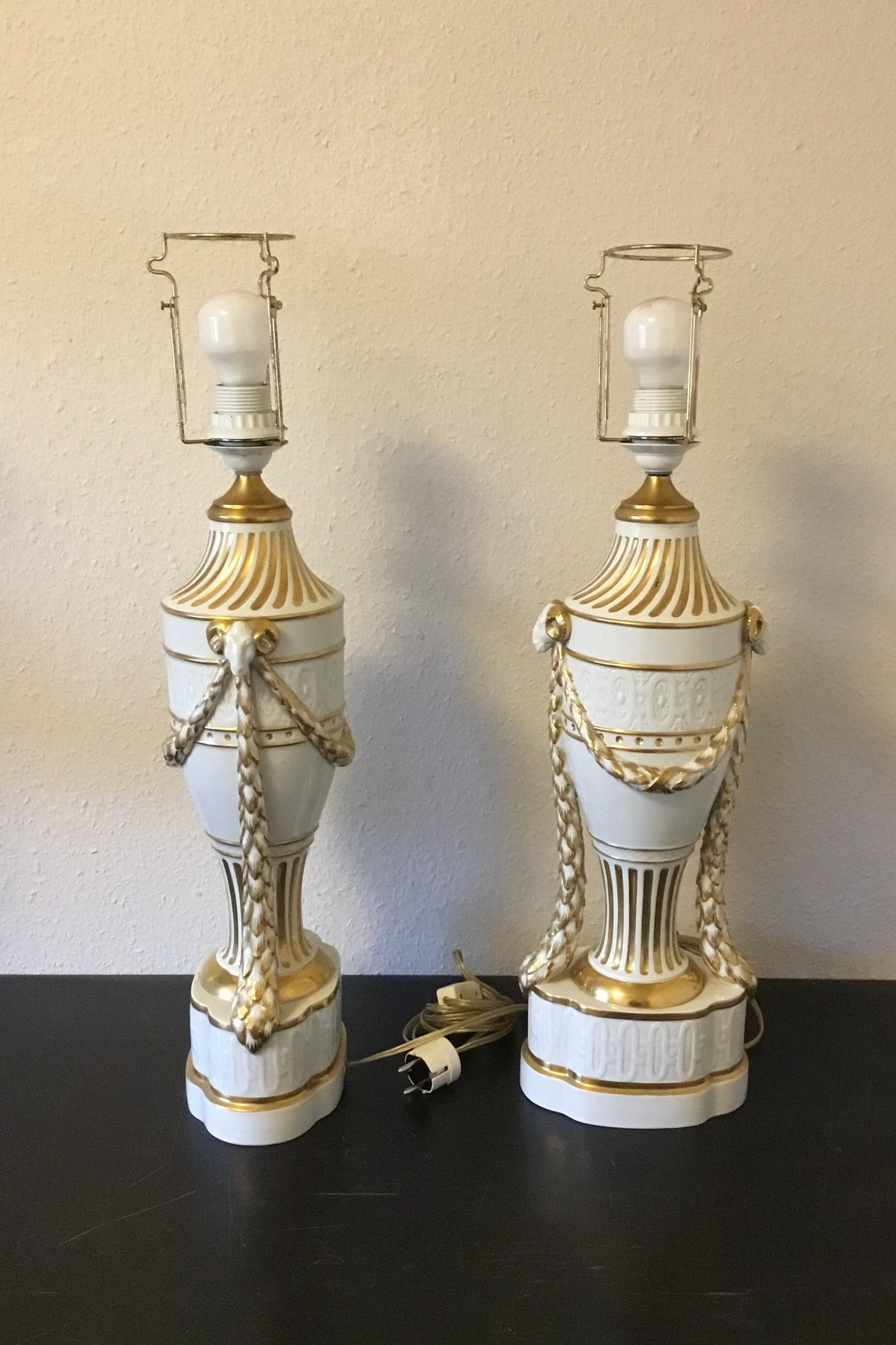 Royal Copenhagen, a pair of baluster-shaped lamps on base decorated with garlands, Ram heads and gold. With Juliane Marie Stamp from 1905-1912. Mounted with EL bulbs and wire. One with a crack otherwise in fine condition. Measures 65 cm / 25 19/32