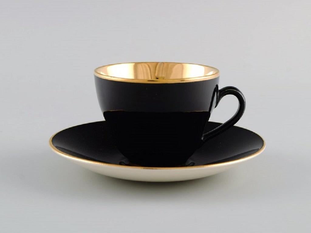 Royal Copenhagen / Aluminia Confetti mocha cup with saucer and sugar bowl in black glazed faience with interior gold. 
Mid-20th century.
The cup measures: 6.8 x 5 cm.
Saucer diameter: 12 cm.
In excellent condition.
Stamped.