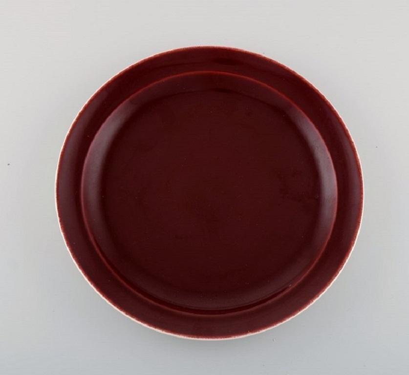 Royal Copenhagen / Aluminia Confetti plate and three large dishes in burgundy red glazed faience. 
Mid-20th century.
Round dish diameter: 27 cm.
Oval dish measures: 38.5 x 25.5 cm.
In excellent condition.
Stamped.
1st factory quality.