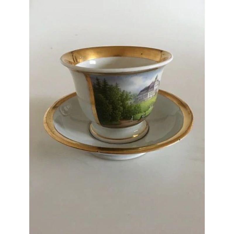 Royal Copenhagen Antique Morning Cup and Saucer with Handpainted Motif of Sorgenfri Castle.

In good condition. The handpainted motif is without wear. The gold looks nice. The handle however has a reparation, and the saucer has a chip underneath.