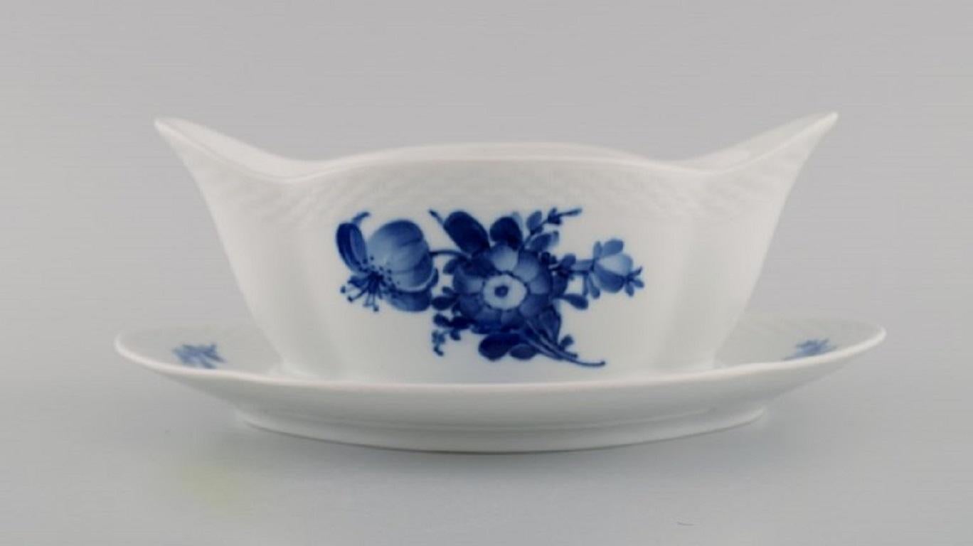 Salsera trenzada de flores azules de Royal Copenhagen sobre soporte fijo. Model No. 10/8159. 
Fechada en 1958.
Medidas: 22,5 x 8,5 cm.
En excelente estado.
Sellado.
1ª calidad de fábrica.