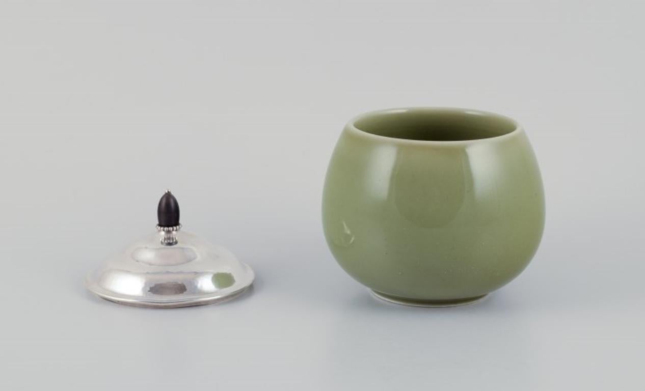 Scandinavian Modern Royal Copenhagen ceramic jar. Silver lid with ebony knob. Celadon glaze. For Sale