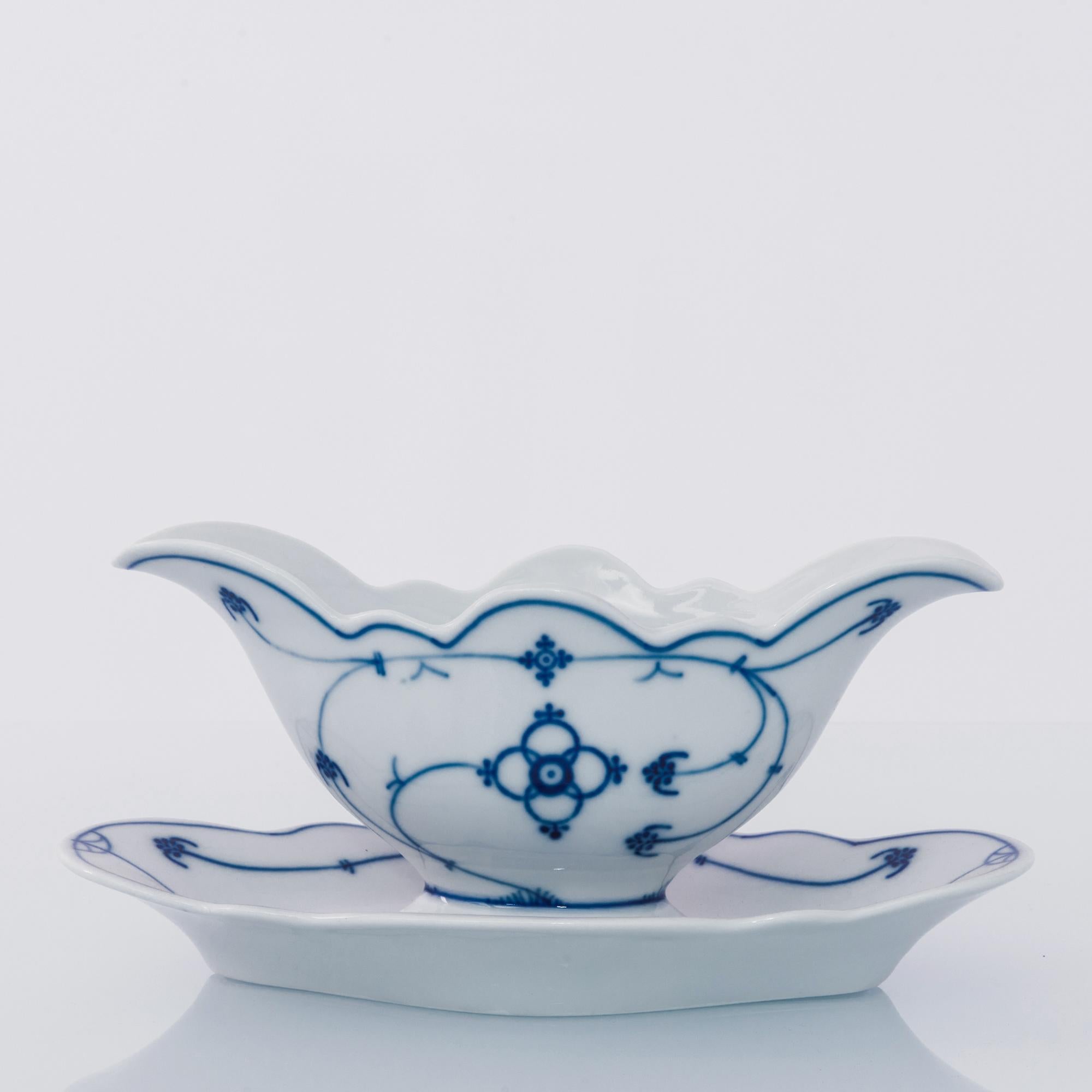 A ceramic sauceboat from the Netherlands, circa 1900. White china is decorated with an intricate pattern of slender stems and symmetrical buds. Laced with the signature Royal Copenhagen blue painted glaze; the delicate contour and out-turned lip of
