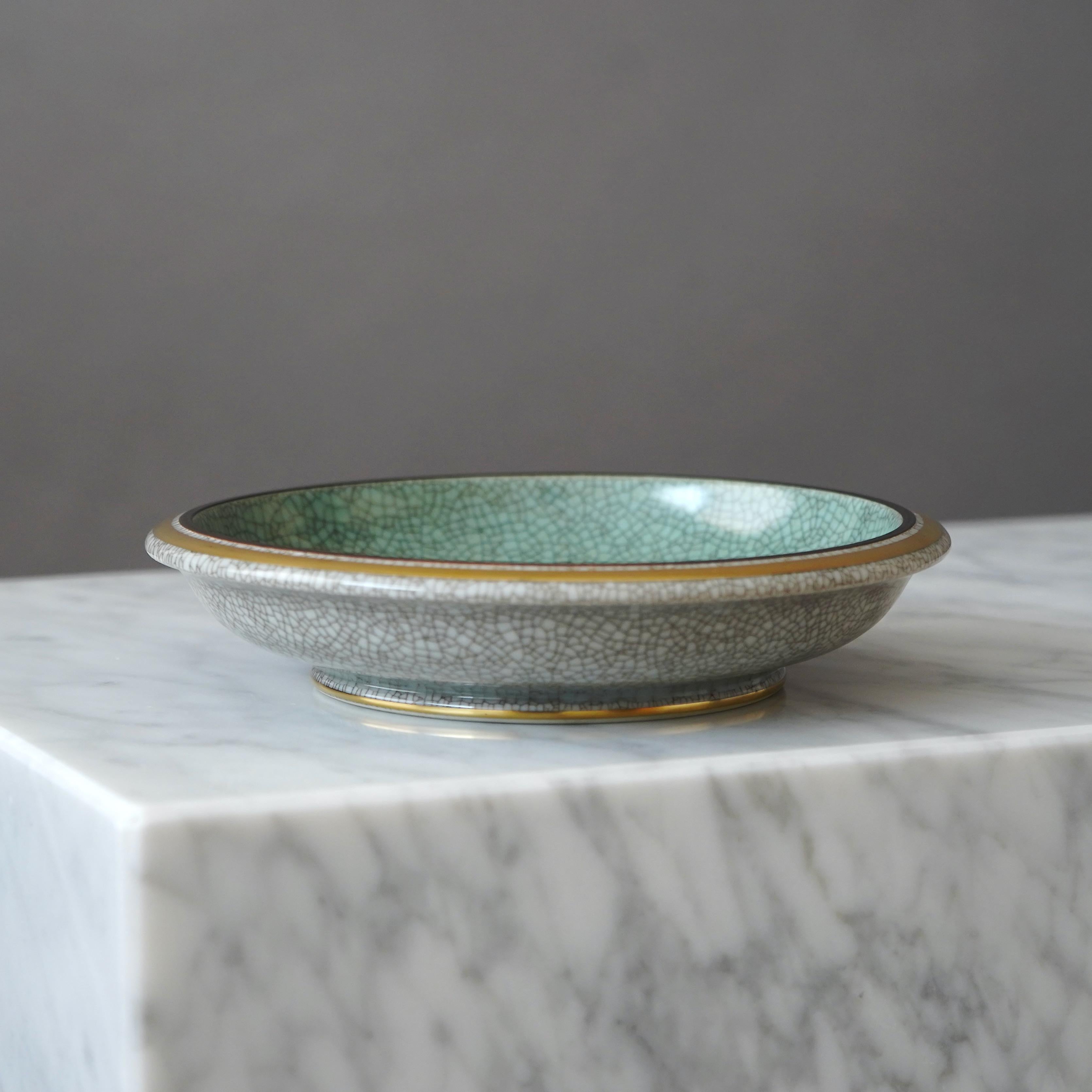Elegant Royal Copenhagen crackle glazed bowl with gilded banding on the rim and base.
Designed by THORKILD OLSEN (1890-1973) for ROYAL COPENHAGEN. Made in Denmark, 1954.

Great condition. Factory second (for no obvious reason). 
Stamped with makers