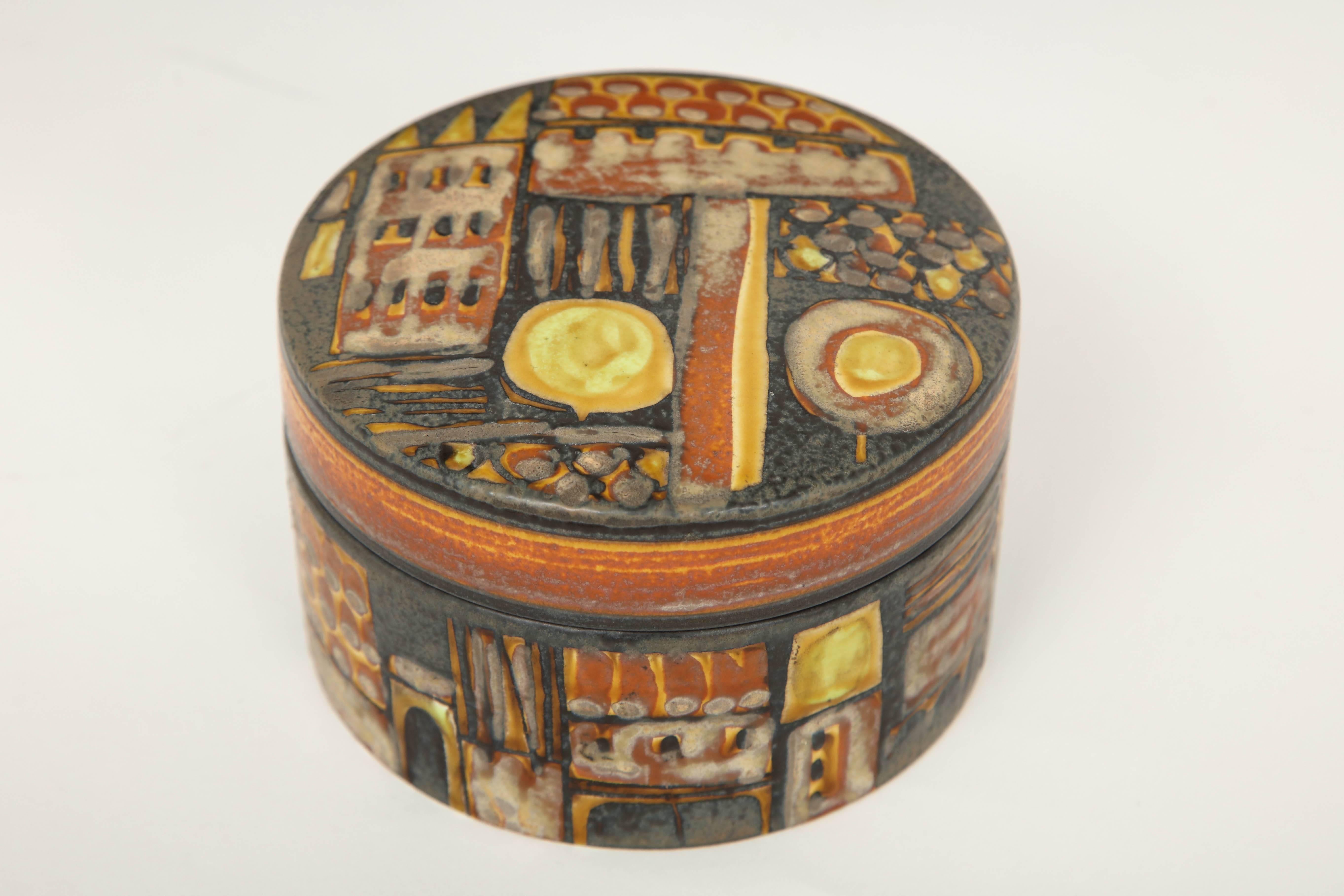 Beautiful colors abound in this Royal Copenhagen Faience Baca box in orange, yellow, chocolate and grey by Johanne Gerber. This cylinder lidded ceramic box was masterfully created with an abstract design circling the box and is perfect for any