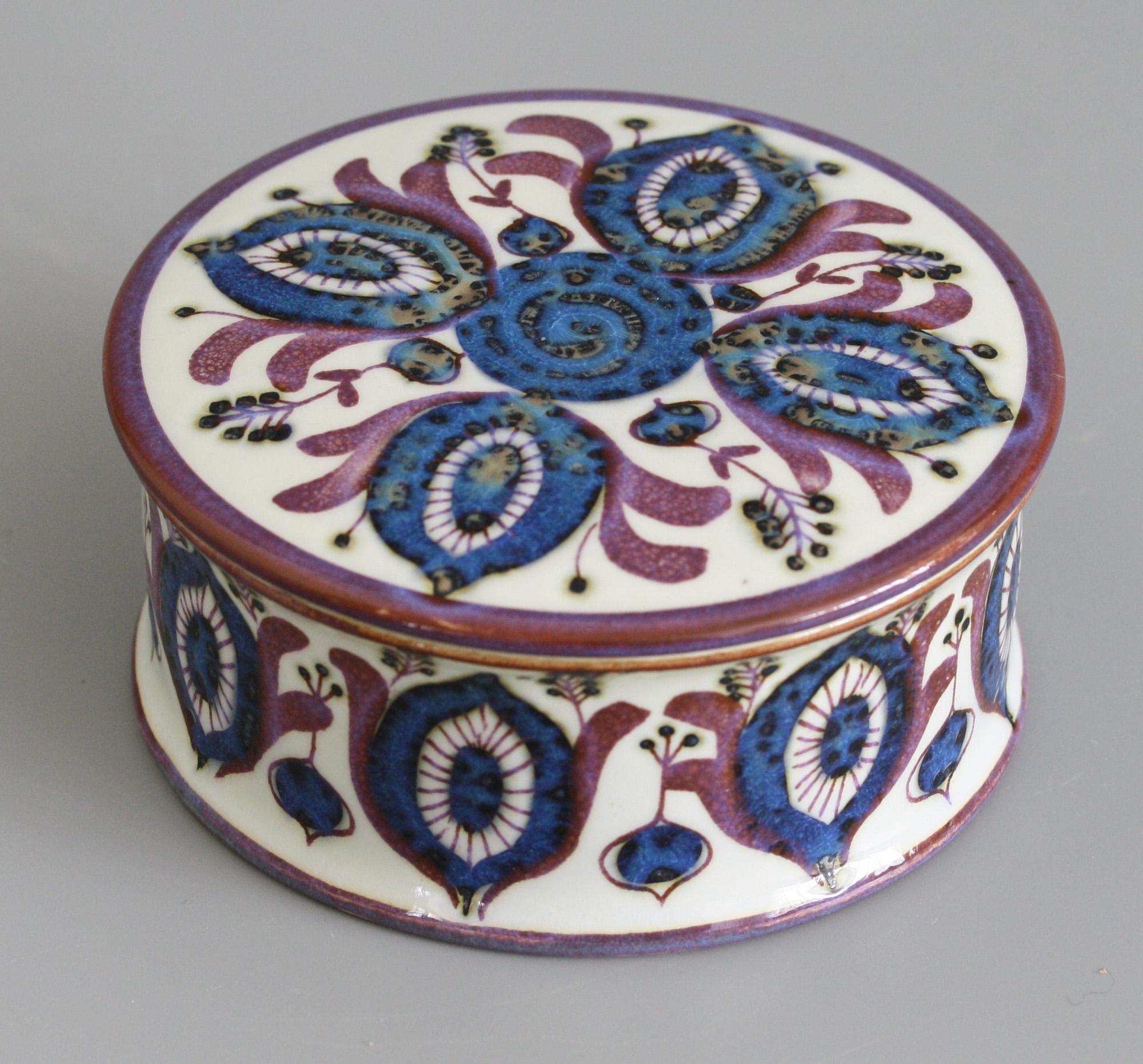 A stylish vintage Royal Copenhagen Faience lidded pot decorated with stylized seed pod designs by Berte Jessen and dating from circa 1970. The wide cylindrical shaped rounded pot has a raised side decorated in slight relief with a continuous pattern