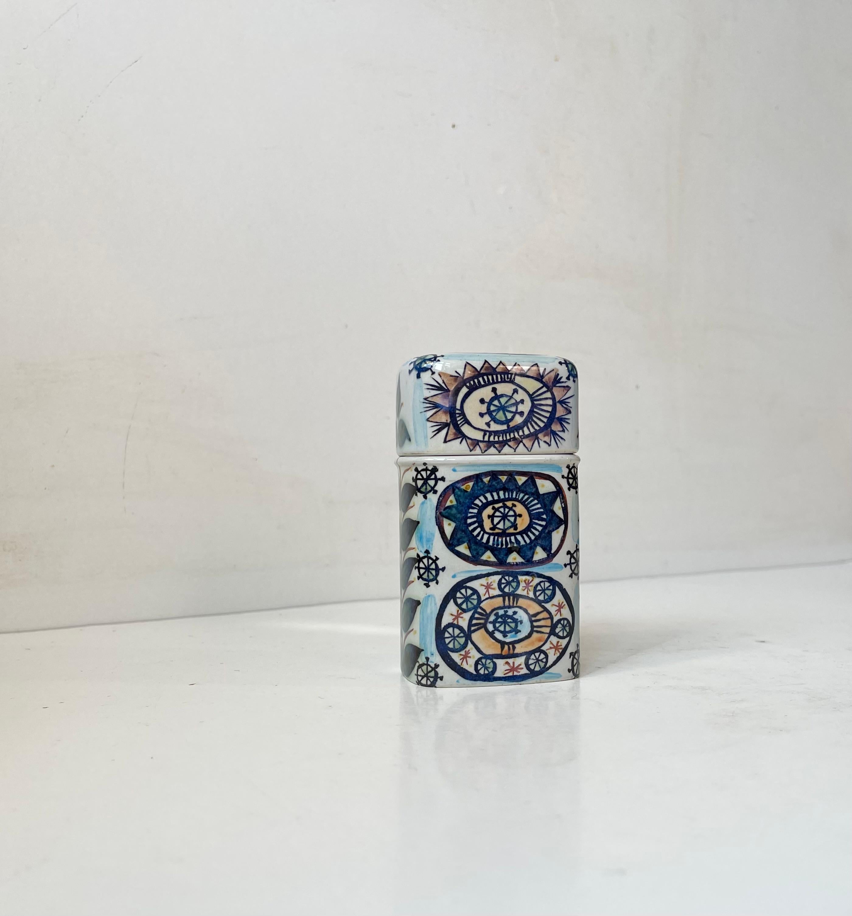 A rare Royal Copenhagen Cigarette Jar/trinket in faience decorated by Norwegian Female artist/designer Marianne Johnson. It is decorated on all sides and features slightly tilted base for easy access to your cigarettes. Designed and manufactured