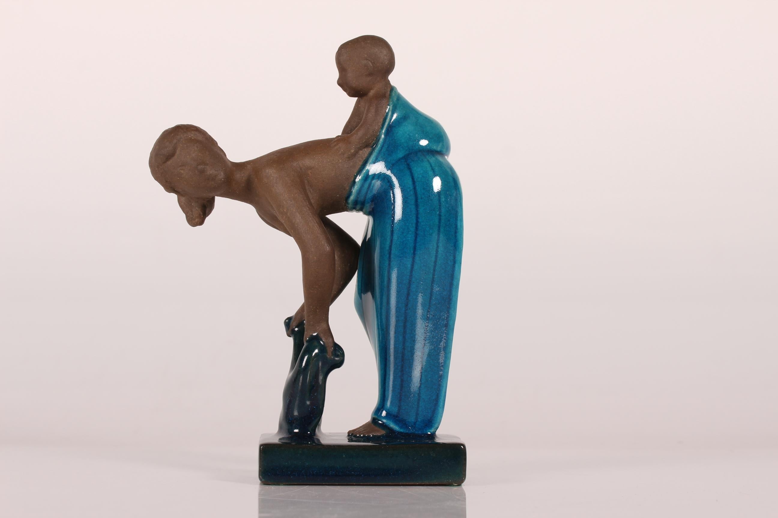 Stoneware figurine of a young woman with her child model no. 21565 designed by Johannes Hedegaard and manufactured by Royal Copenhagen

This figurine is made in 1958 and partly decorated with dark blue glaze and signed Johannes Hedegaard + model