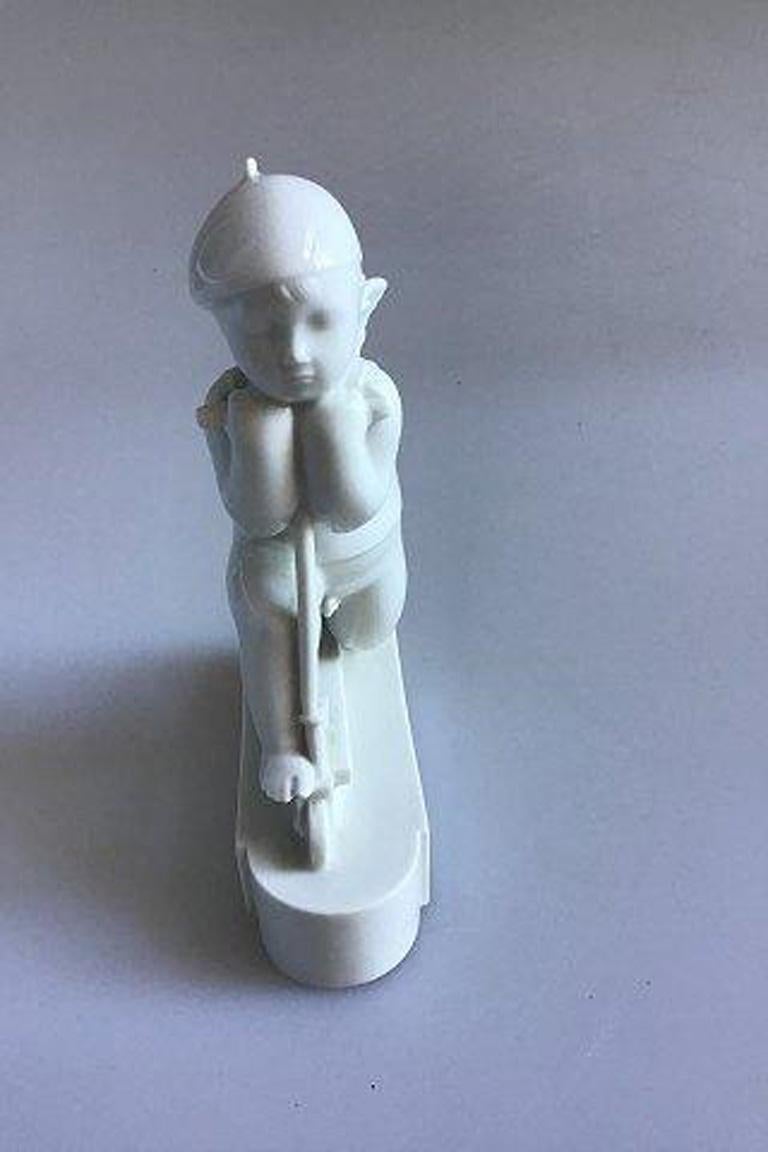 Royal Copenhagen figurine, cupid on scooter no 12477 (1931) Arno Malinowski Blanc de chine, 

Measurement: 15.5 cm/6.1 inches.
 